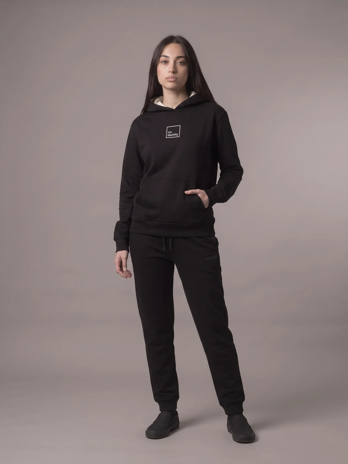Black regular fit hoodie in organic cotton, Unidentity Core Hoodie, full-length front view worn by woman with black Core joggers, streetwear #color_black