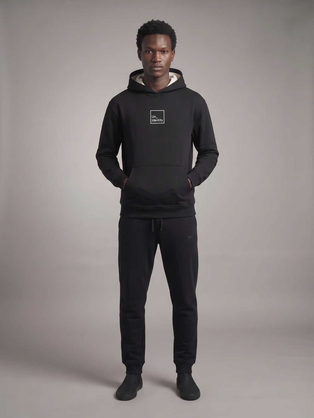Black heavyweight hoodie, Unidentity Core Regular Fit Hoodie, full-length front view on man with black Core Regular Fit Joggers, sustainable fashion #color_black