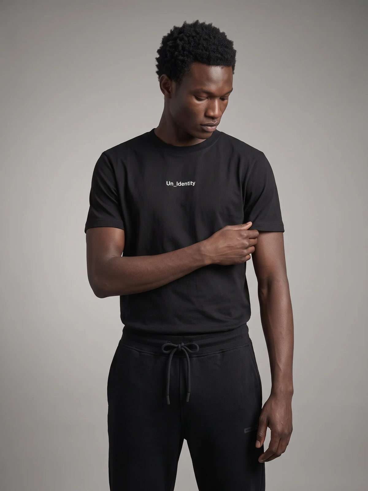 Black long fit t-shirt, Unidentity Gem Tee, front view on man tucked into black Core Regular Fit Joggers, streetwear from Dubai #color_black