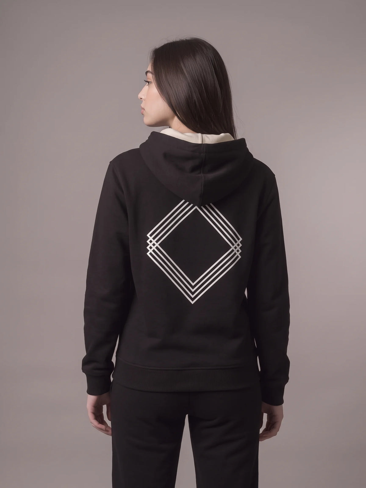 Black heavyweight hoodie in organic cotton, Unidentity Gem Hoodie, back view on woman with large white diamond logo print, 390gsm Dubai streetwear #color_black