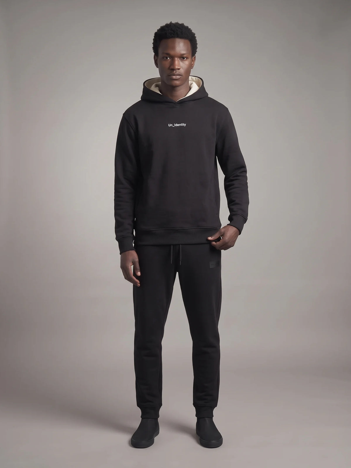 Black heavyweight hoodie, Unidentity Gem Regular Fit Hoodie, full-length front view on man with black Core Regular Fit Joggers, streetwear from Dubai #color_black