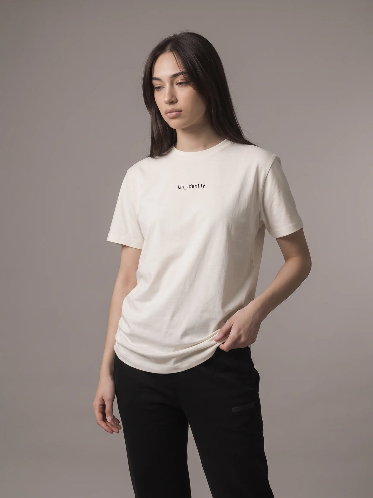 White long fit t-shirt in organic cotton, Unidentity Gem Tee, front view worn by woman showing the minimal Un_Identity chest wordmark, 210gsm #color_white