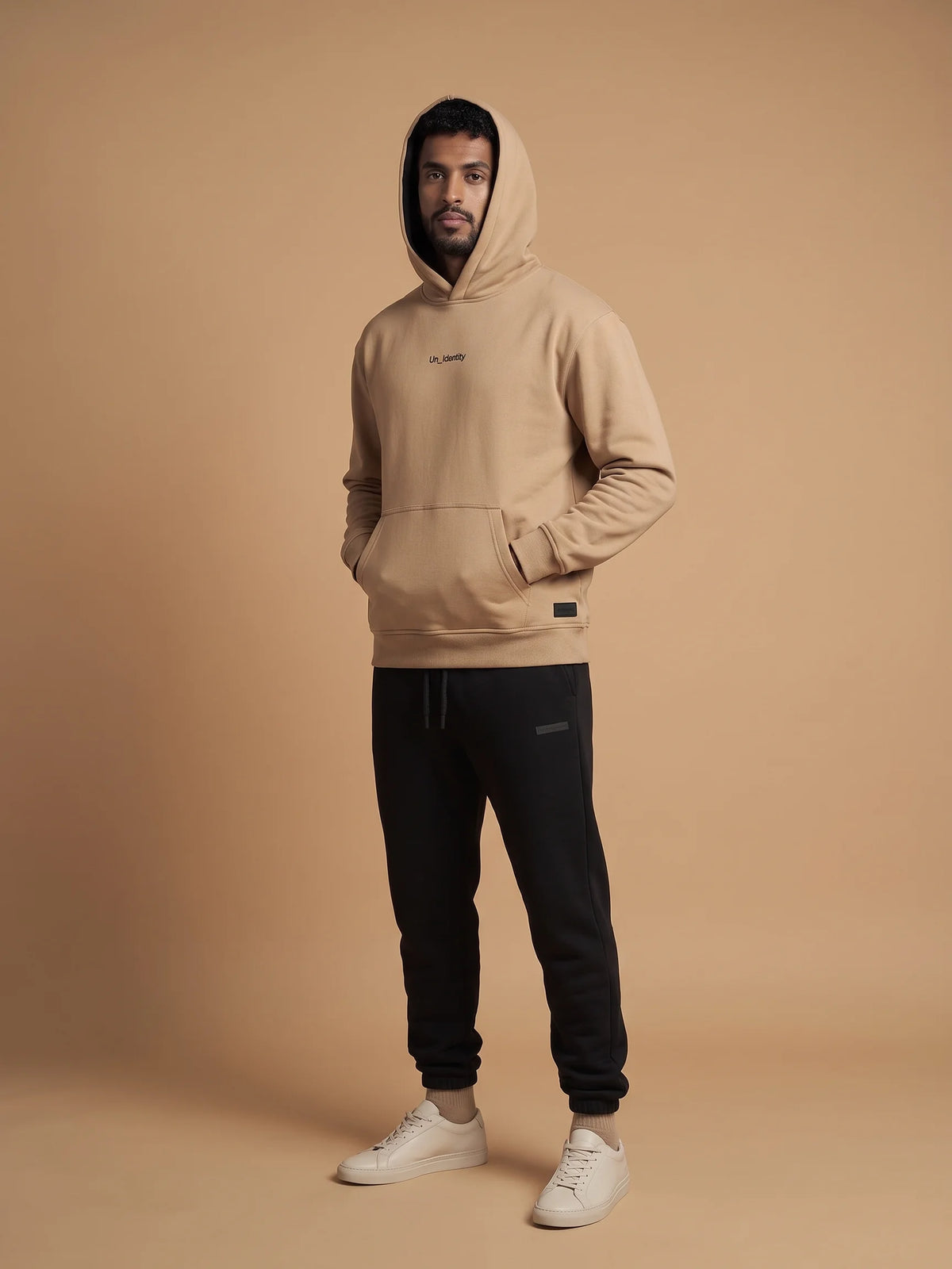 Beige heavyweight hoodie in organic cotton, Unidentity Soul Hoodie, full-length front view worn by man with hood up and black Core joggers, 390gsm #color_beige