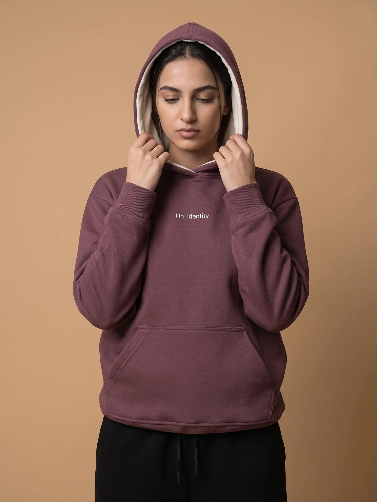 Plum heavyweight hoodie, Unidentity Soul Regular Fit Hoodie, front view of the chest logo worn by woman with hood up, UAE streetwear #color_plum