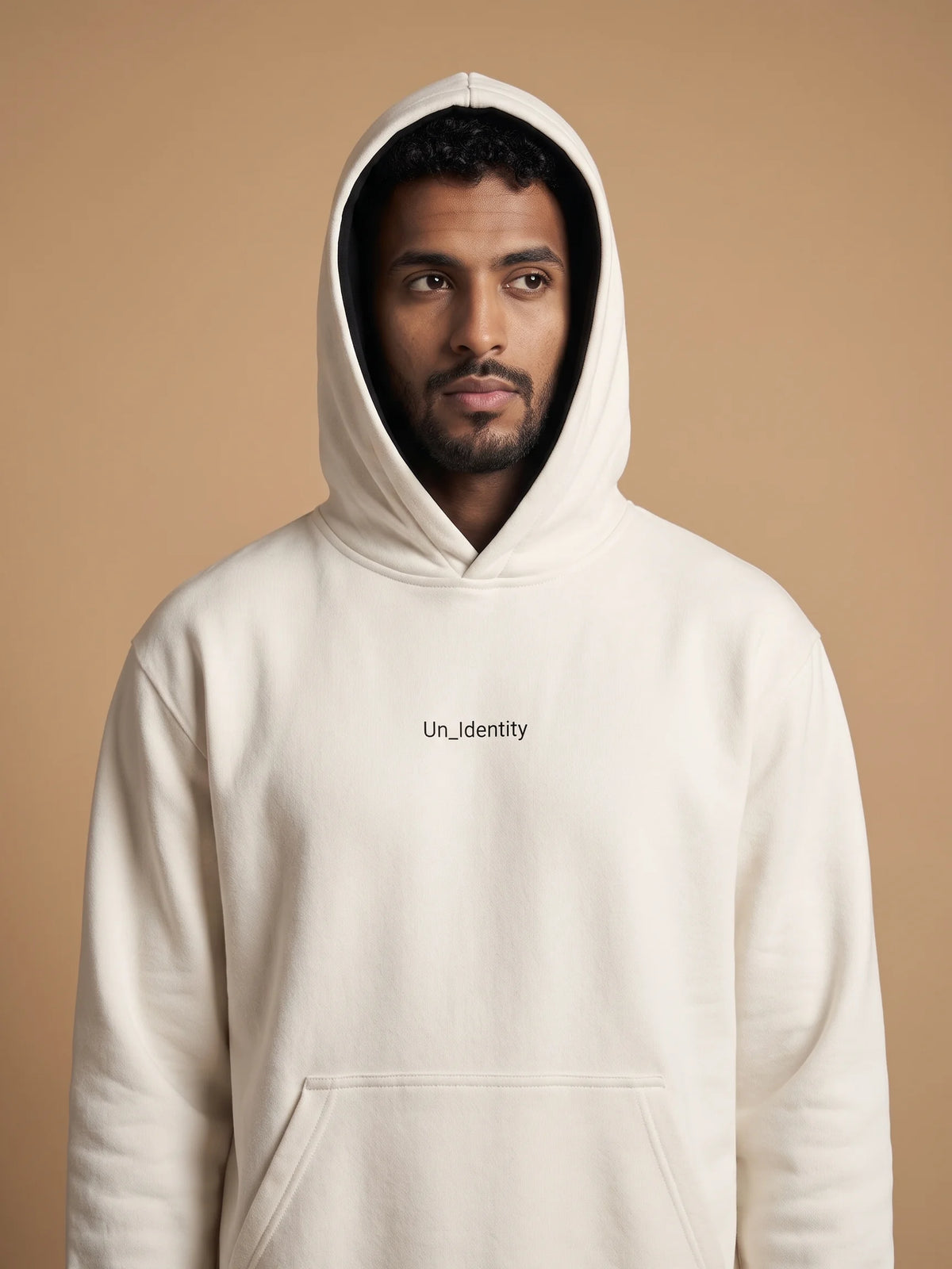 White heavyweight hoodie, Unidentity Soul Regular Fit Hoodie, front close-up of the chest logo worn by man with hood up, streetwear brand in Dubai #color_white