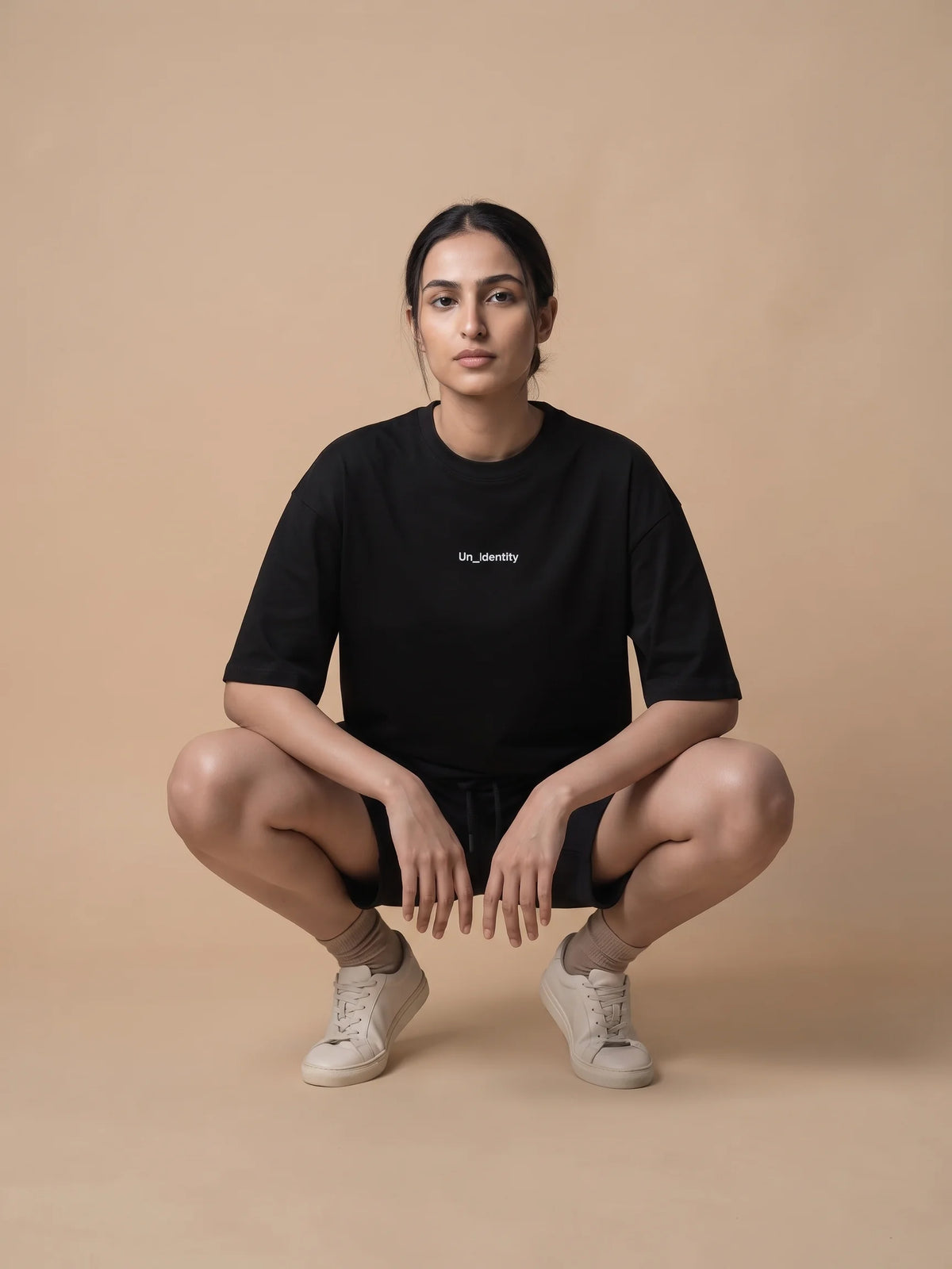 Black organic cotton t-shirt, Unidentity Soul Oversized Tee, front view of the oversized fit worn by woman crouching, sustainable streetwear #color_black