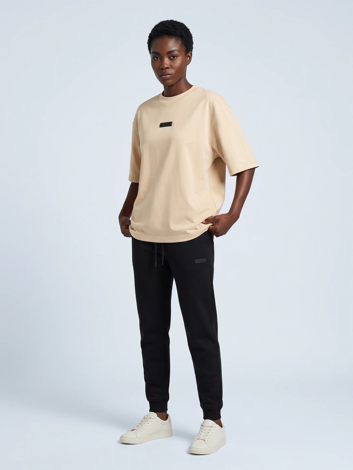 Beige organic cotton t-shirt, Unidentity Identity Tee, full-length front view with black 3D chest patch and Core joggers, from Dubai #color_beige