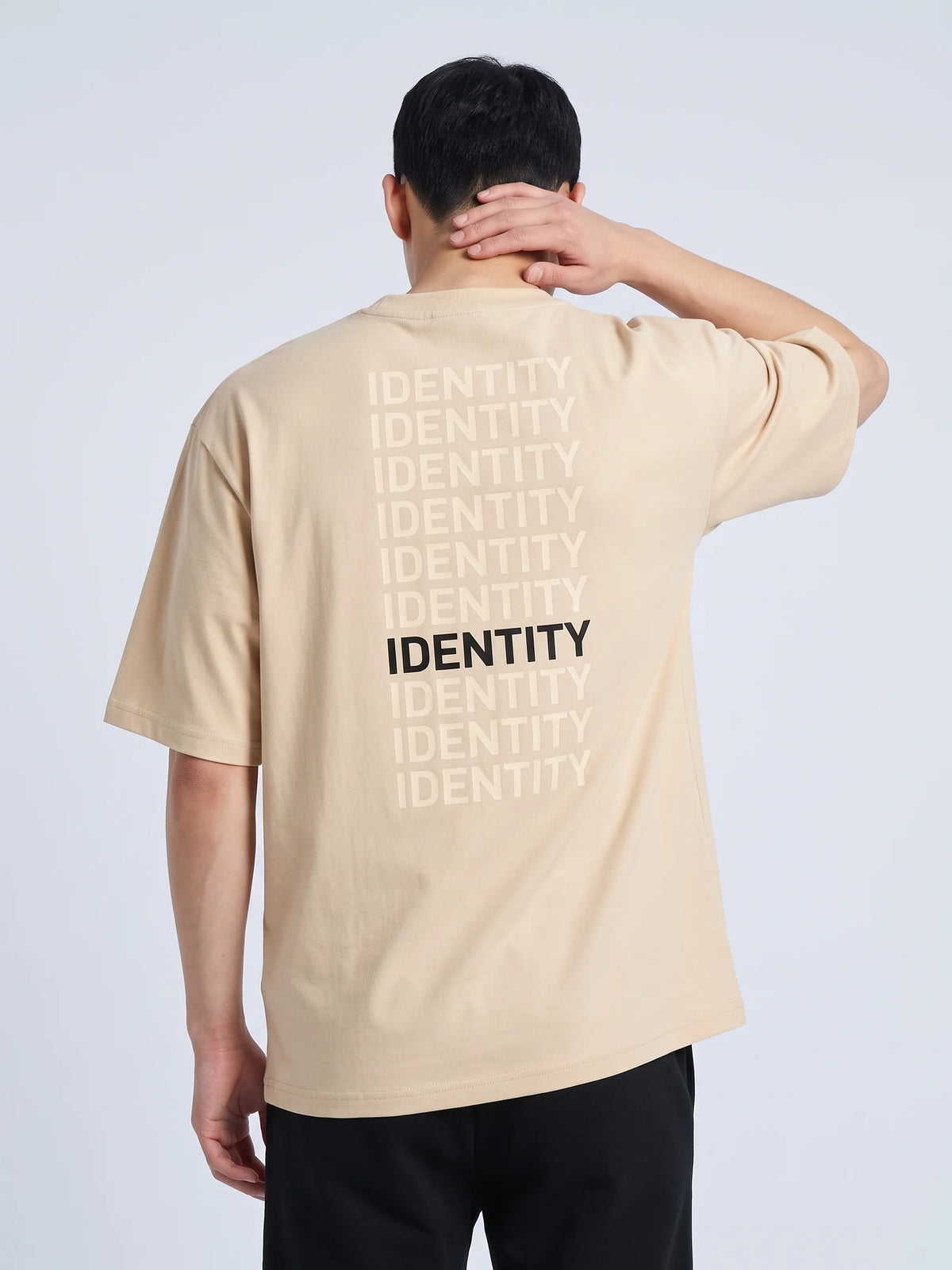 Beige oversized t-shirt, Unidentity Identity Oversized Tee, back close-up of the IDENTITY typographic print worn by man, hand on his neck, streetwear #color_beige