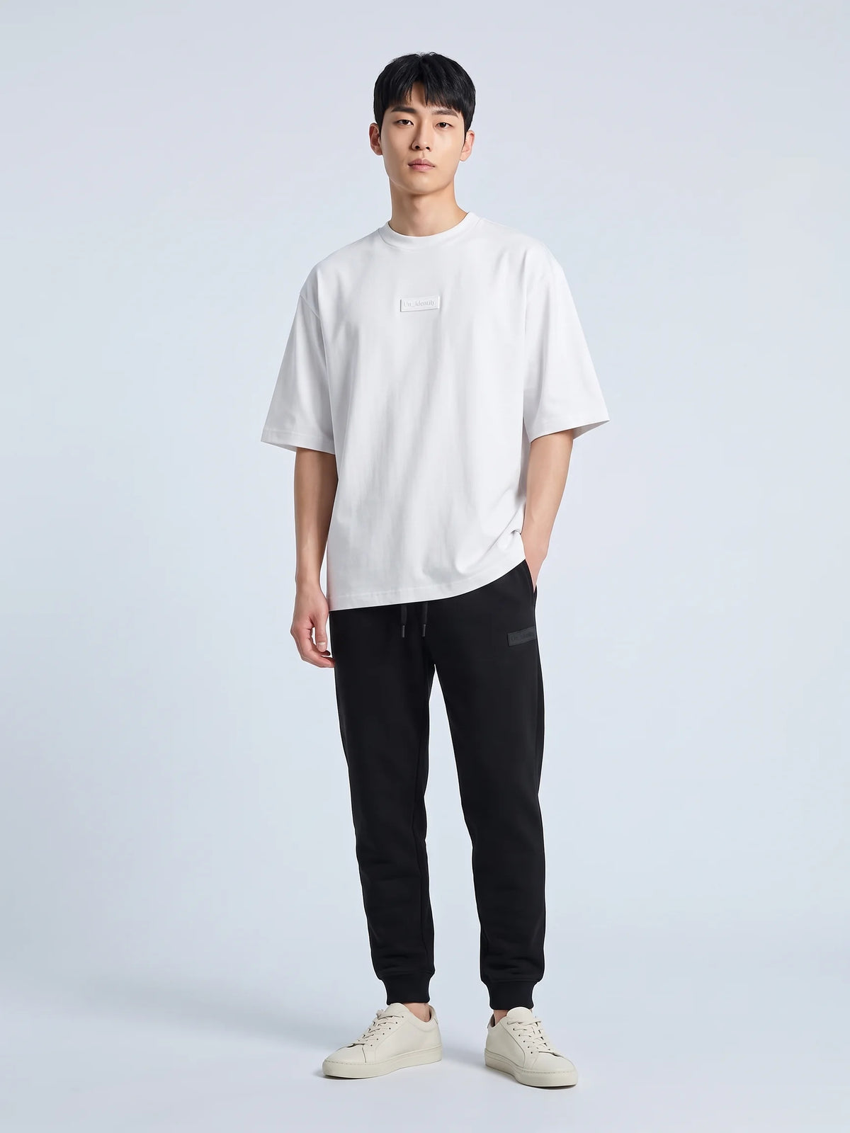 White organic cotton t-shirt, Unidentity Identity Tee, full-length front view with tonal 3D chest patch and black Core joggers, UAE streetwear #color_white