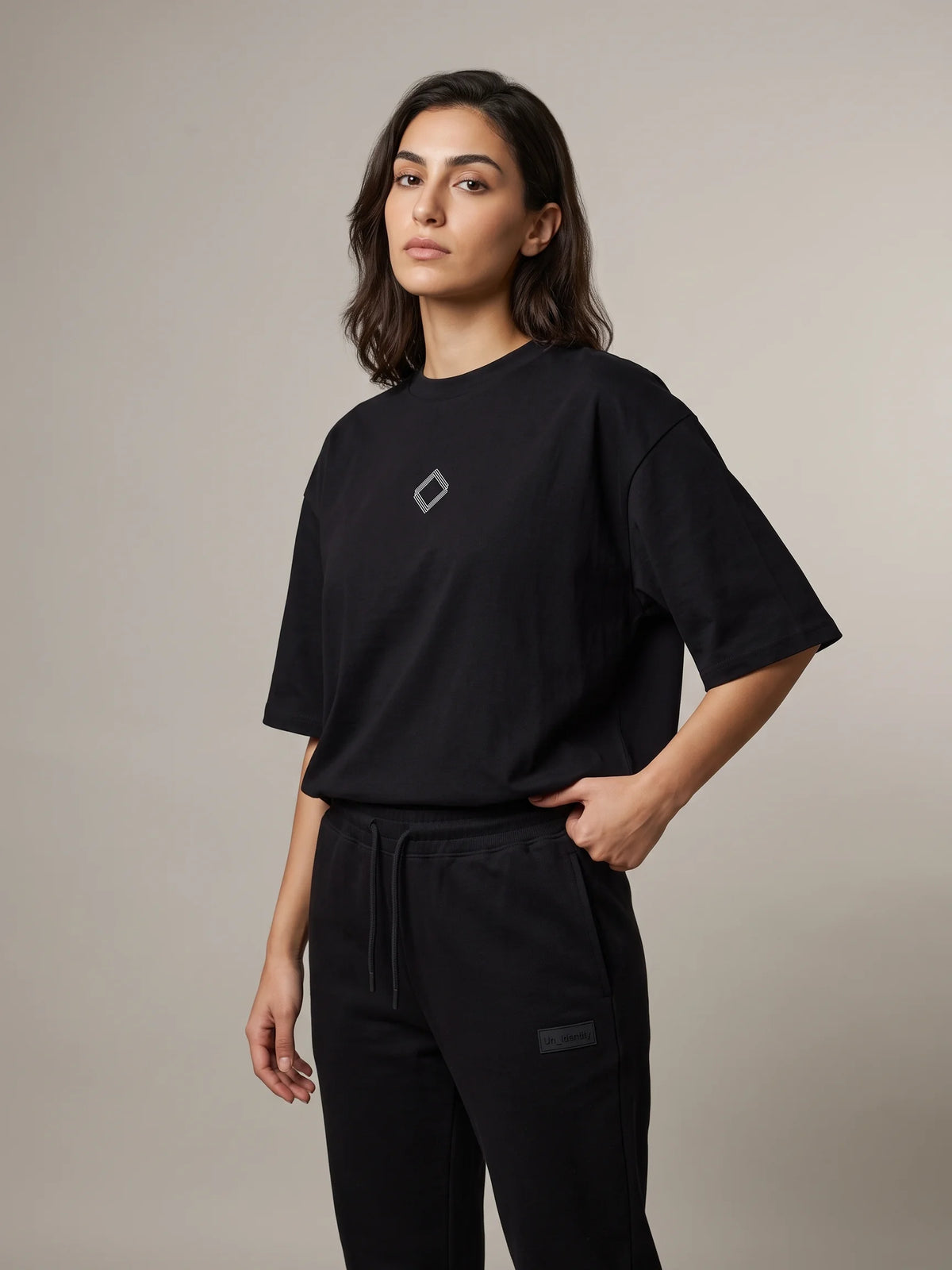 Black organic cotton t-shirt, Unidentity Trace Oversized Tee, three-quarter front view of the diamond chest logo, styled with Core joggers #color_black