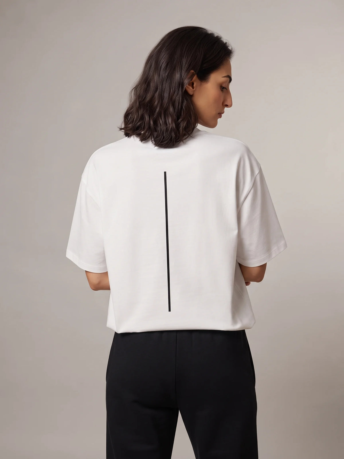 White oversized t-shirt, Unidentity Trace Oversized Tee, back view worn by woman showing the black vertical line print, sustainable streetwear #color_white