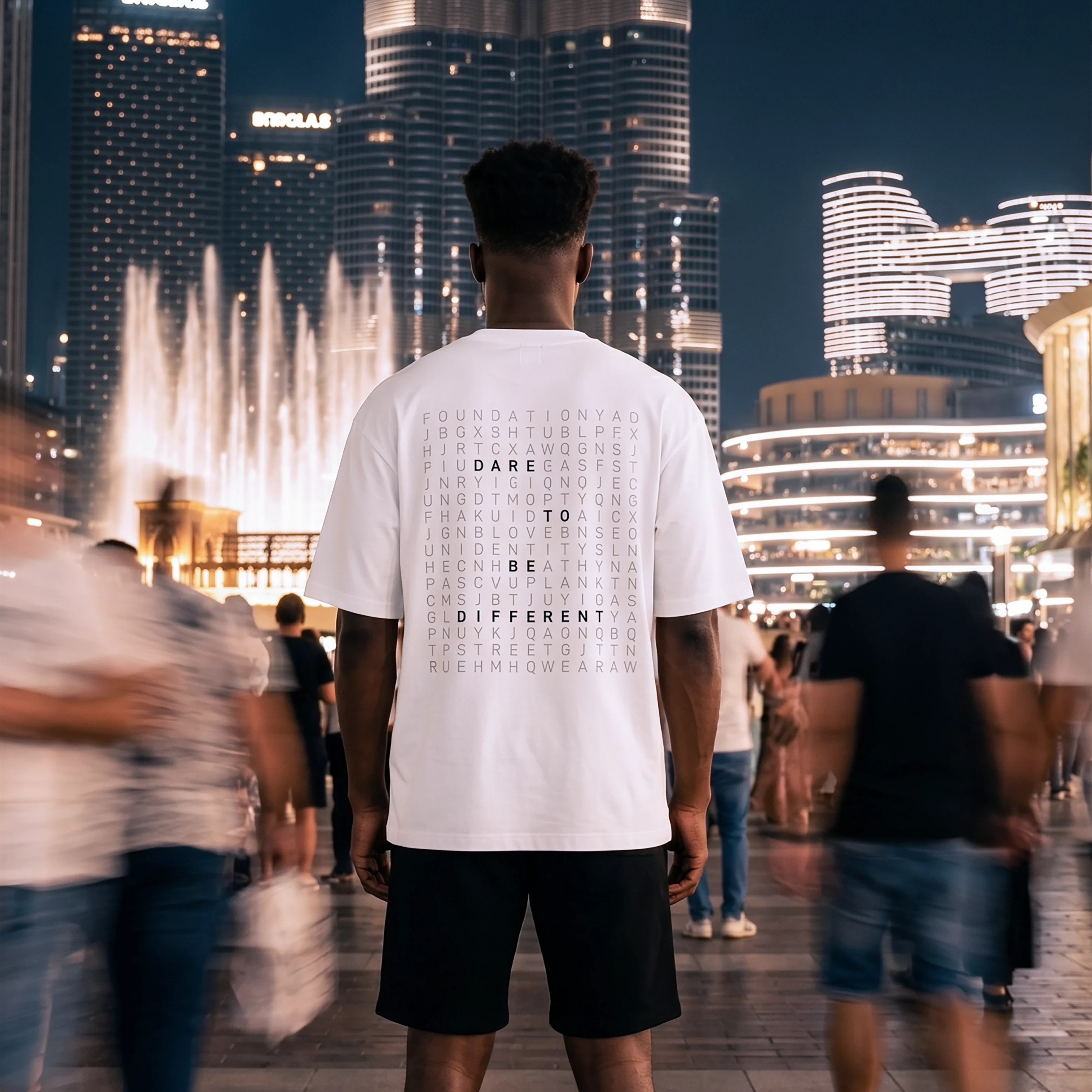 Person wearing a white t-shirt with text in a cityscape at night