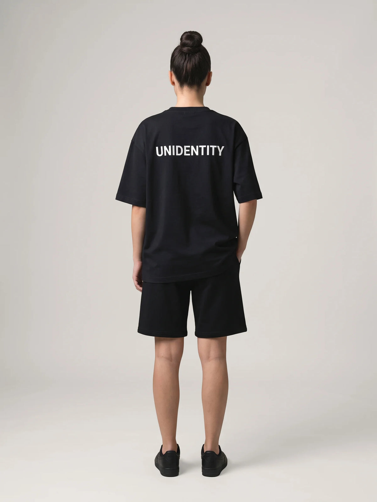 Black heavyweight oversized t-shirt in organic cotton, Unidentity You Tee, full-length back view of the white UNIDENTITY logo, streetwear from Dubai #color_black