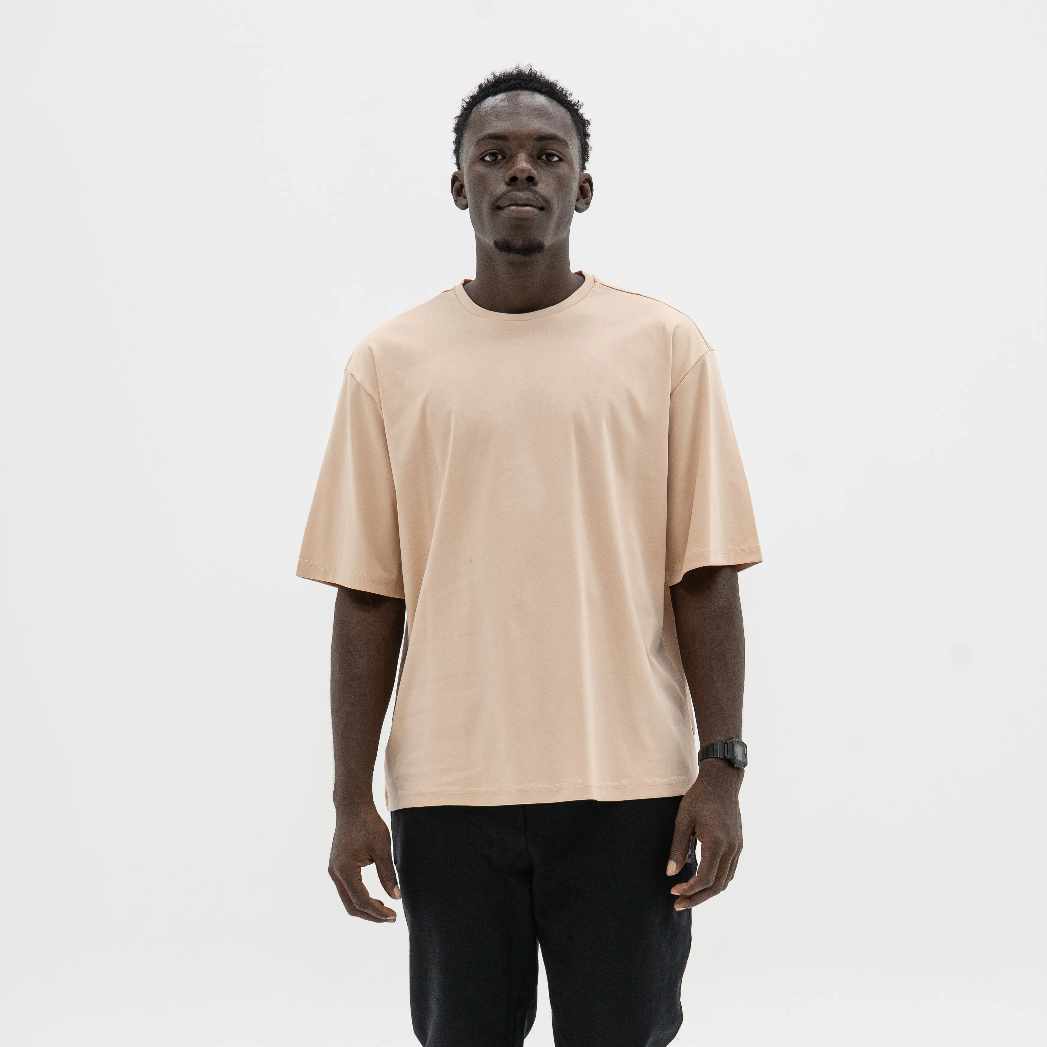 Man wearing a beige t-shirt and black pants on a white background. #color_beige