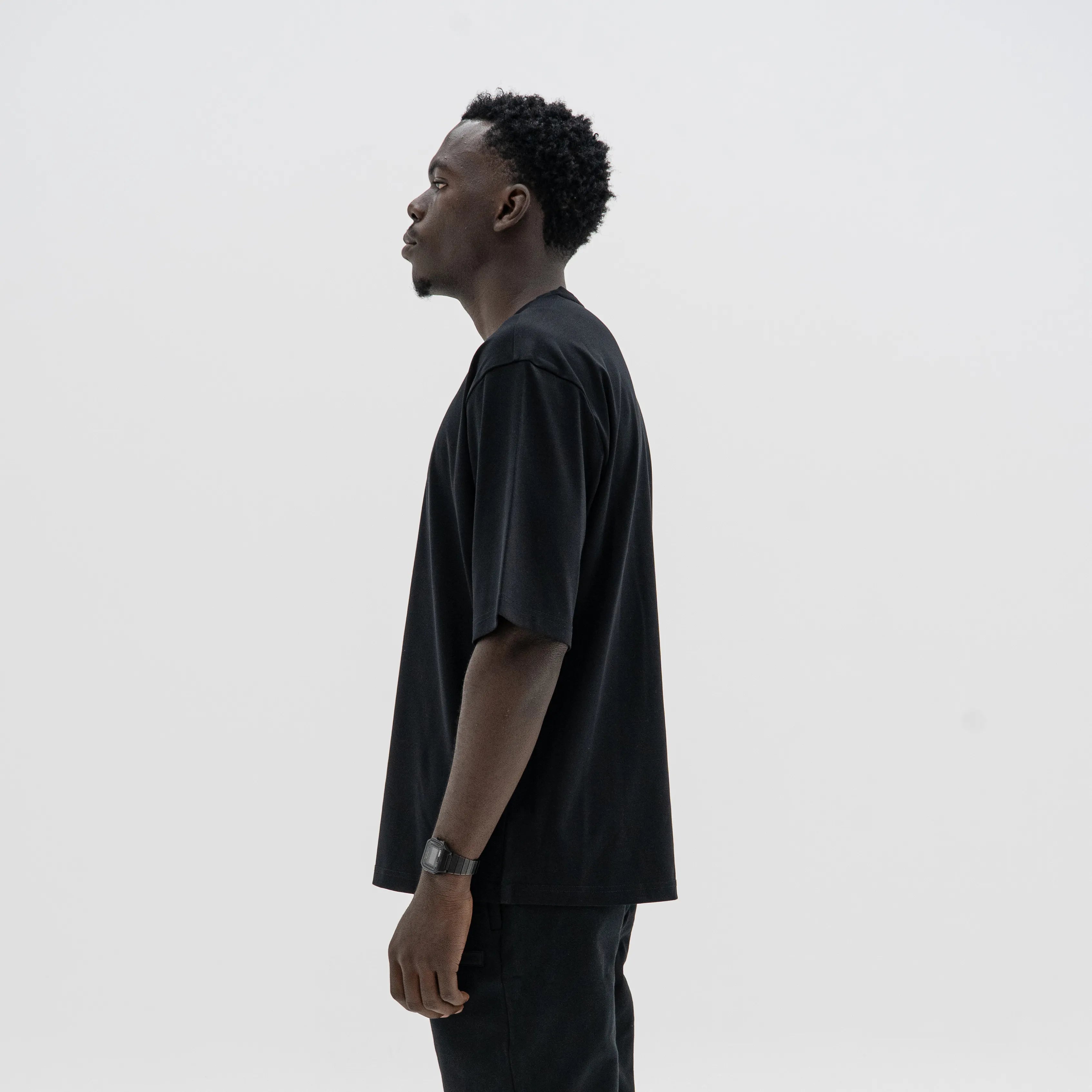 Man wearing a black t-shirt against a plain background. #color_black