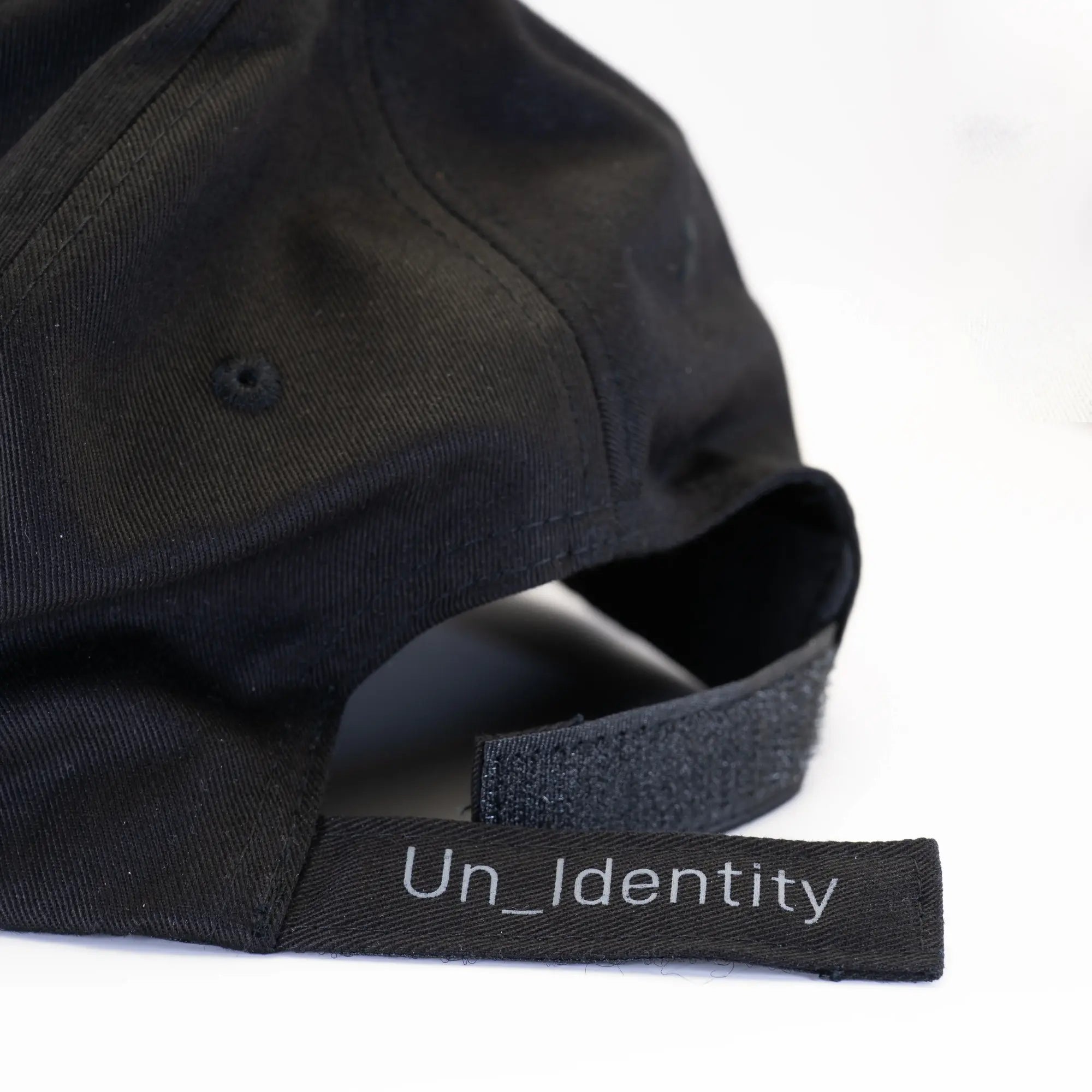 Black cap with Unidentity label on the unfastened back hook-and-loop strap