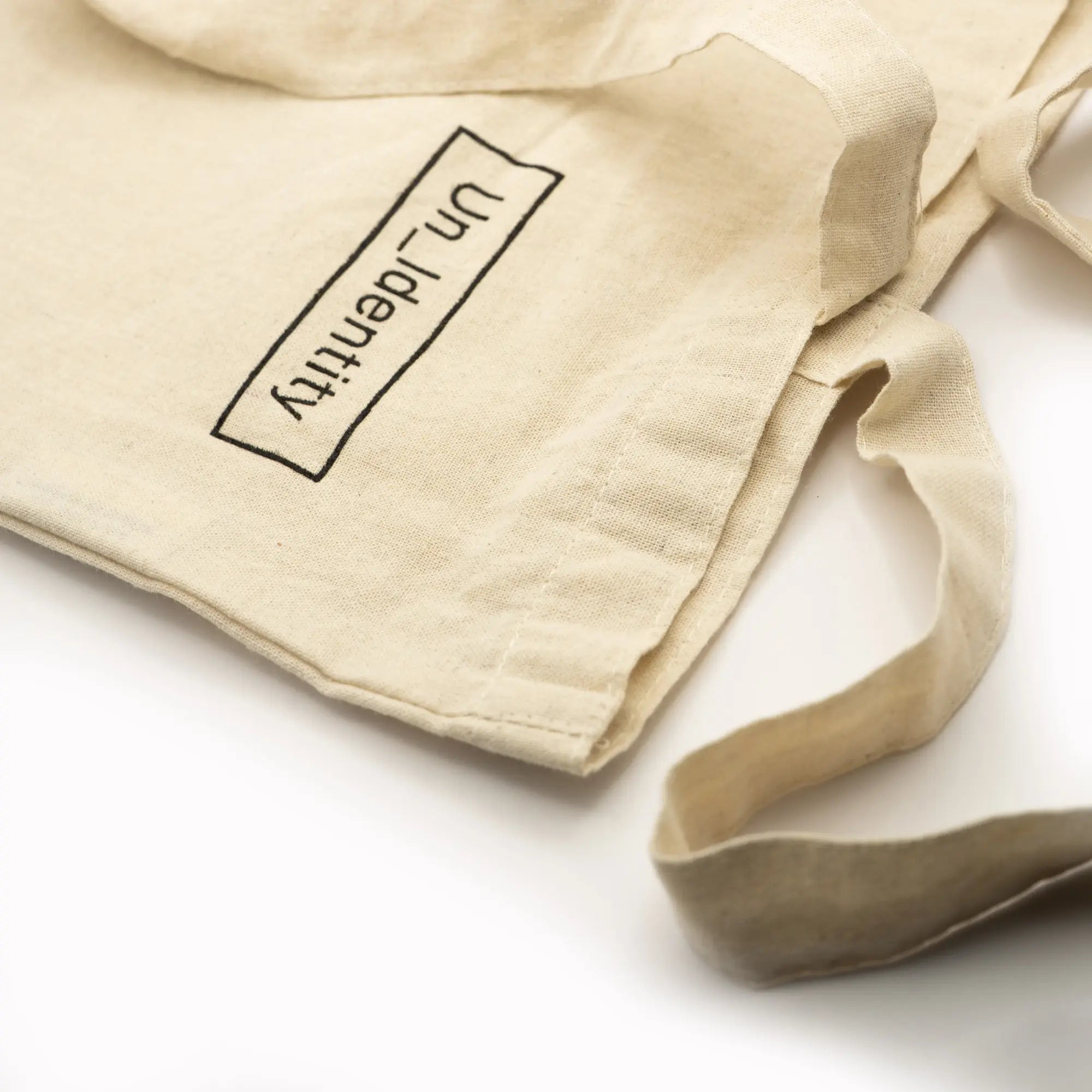 Close up of Unidentity logo text on beige tote bag
