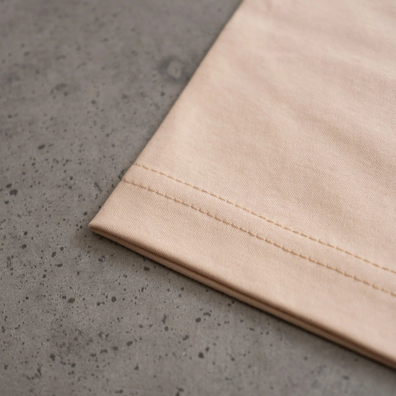 Close-up of beige fabric on a gray concrete surface. #color_beige