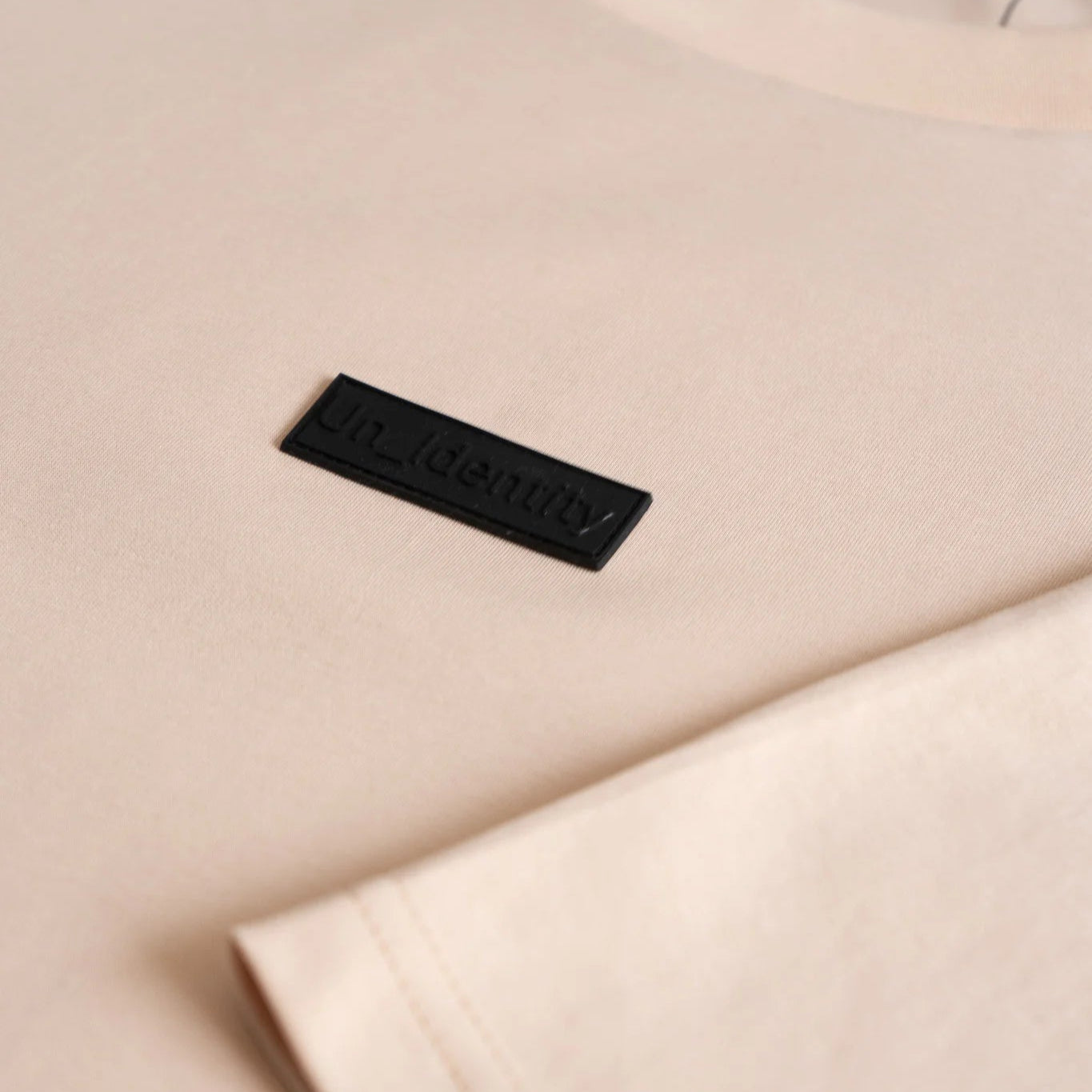 Close-up of a beige garment with a black label on a light background. #color_beige