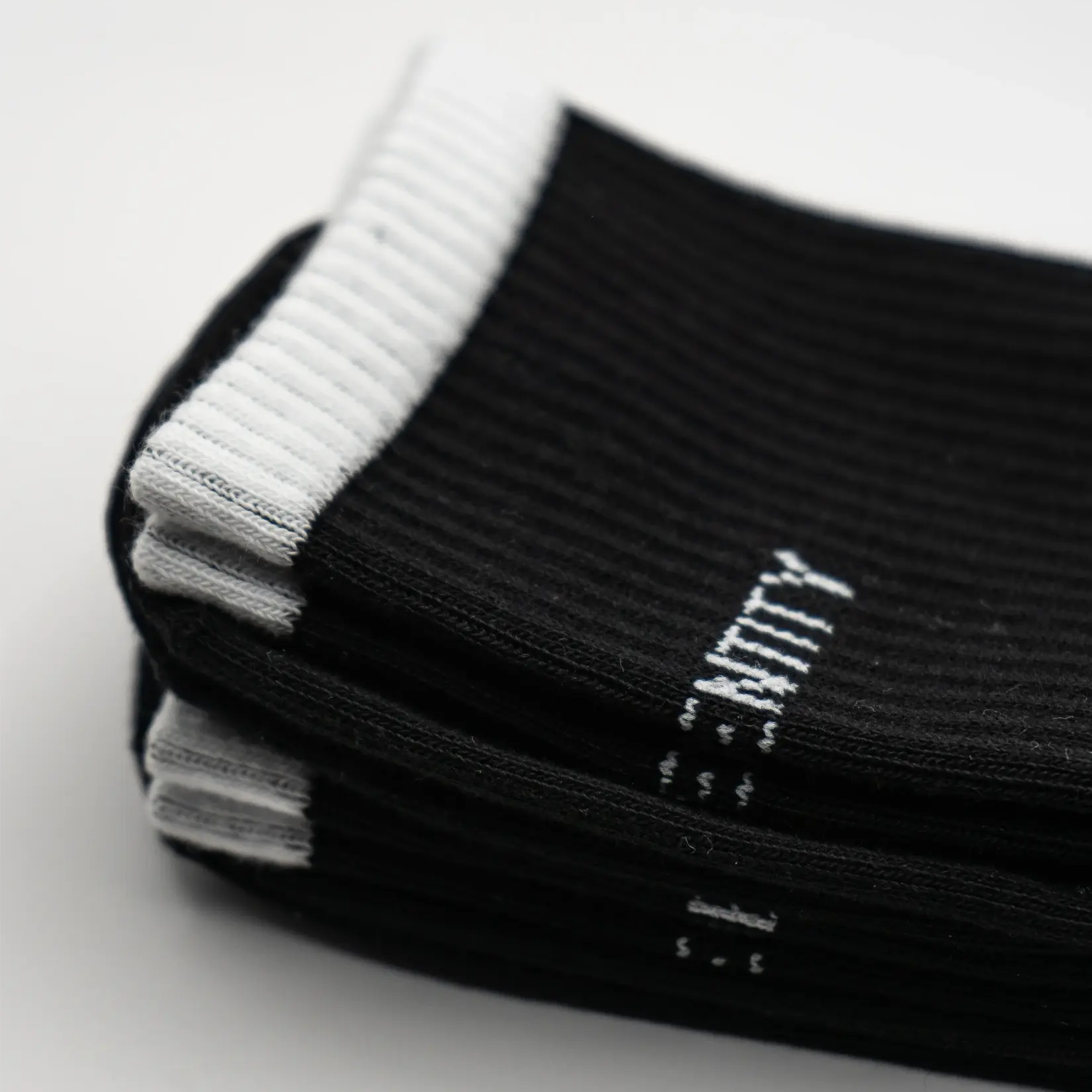 Stack of black socks with white ribbing and white branding text
