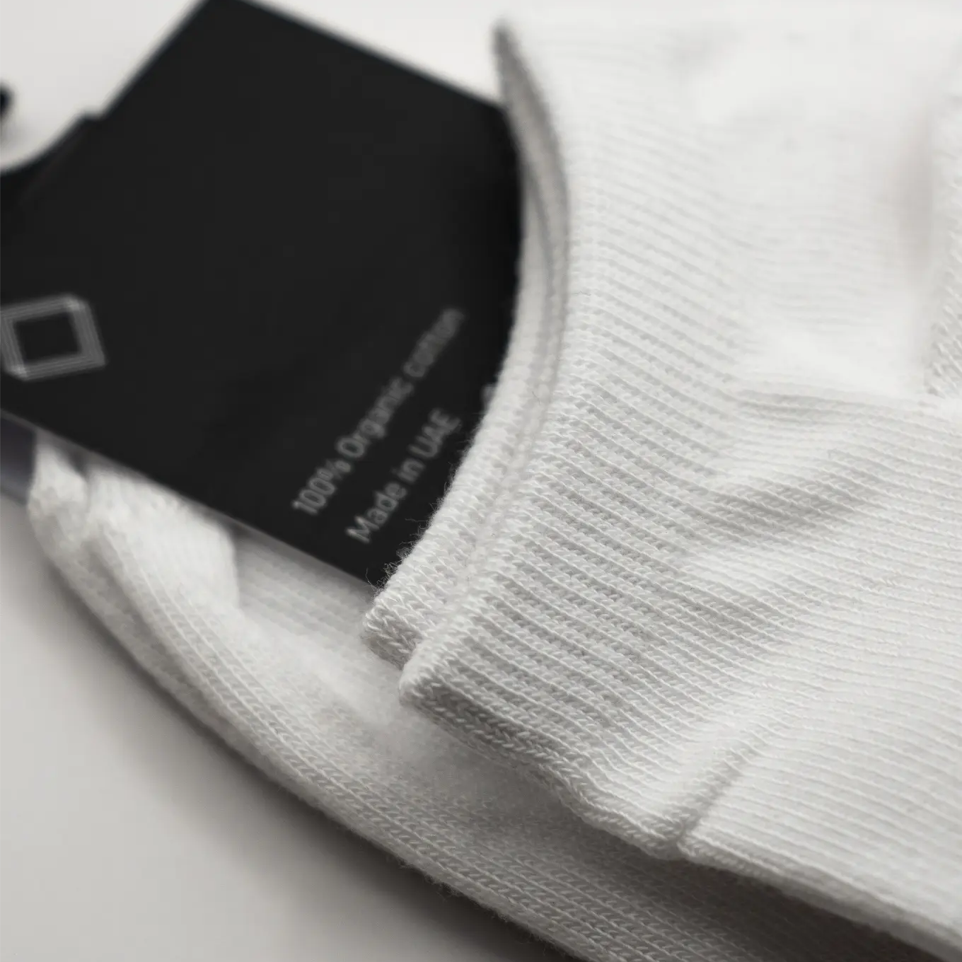Close-up of a white sock with a black label. #color_white