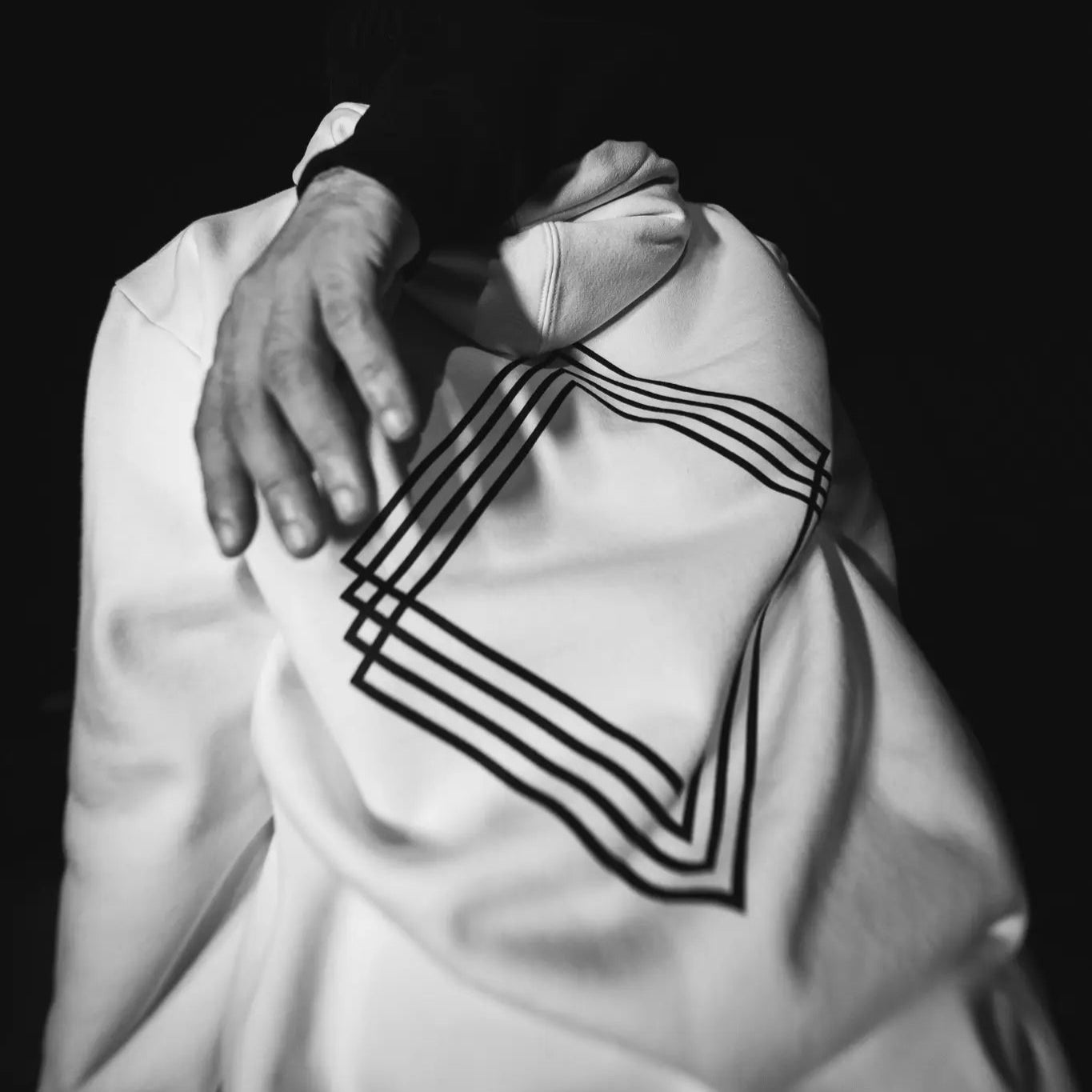 Person wearing white garment with black geometric patterns. #color_white