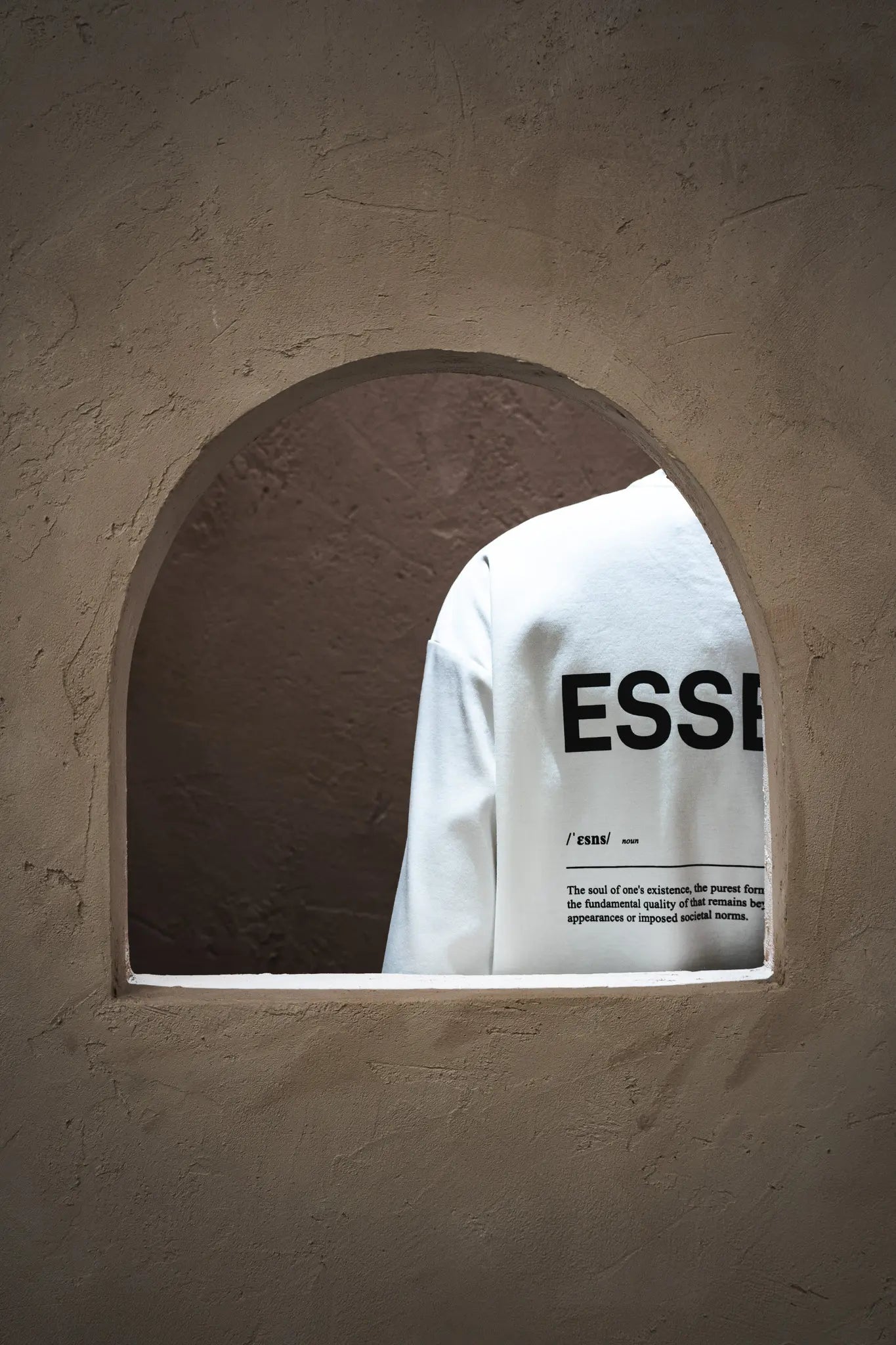White shoulder part of Unidentity T-shirt showing through a stone archway