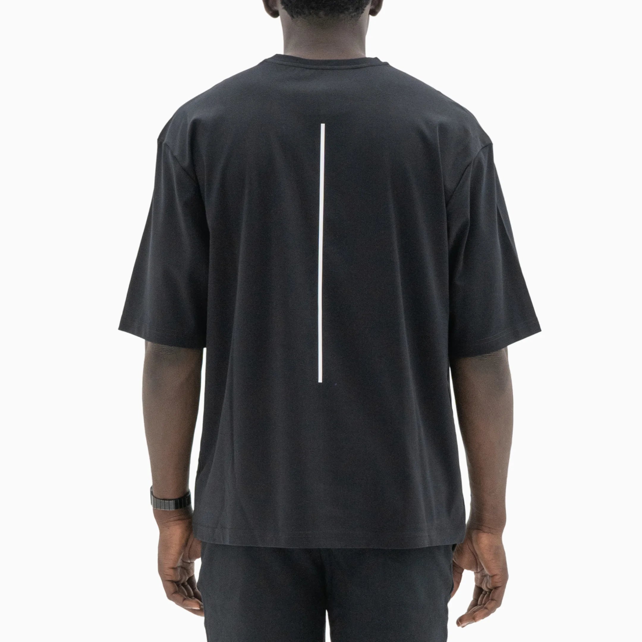 Person wearing a black t-shirt with a white line on the back against a plain background. #color_black