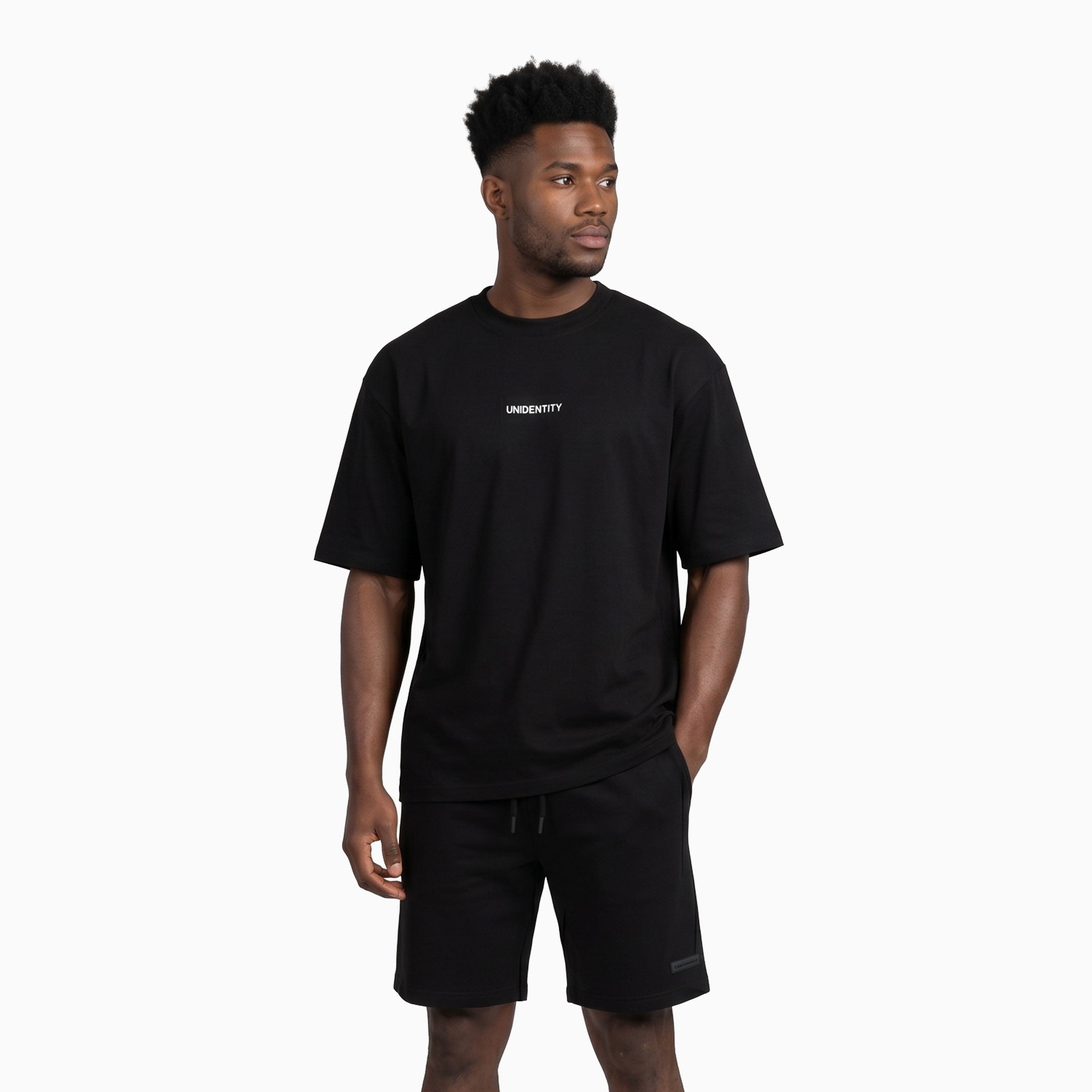 Man wearing a black t-shirt with 'UNIDENTITY' logo on a white background. #color_black