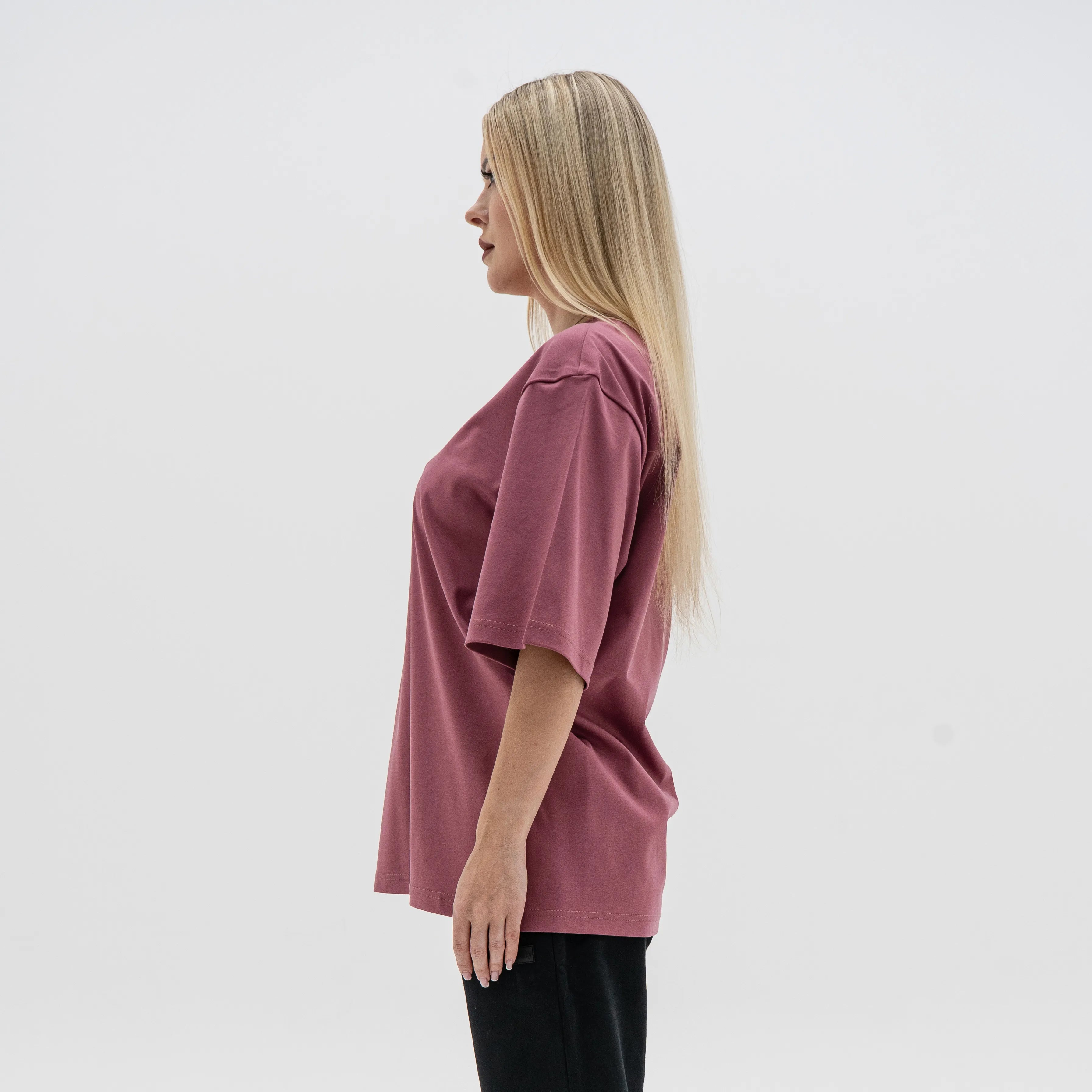 Woman wearing a loose-fitting maroon t-shirt against a plain background. #color_plum