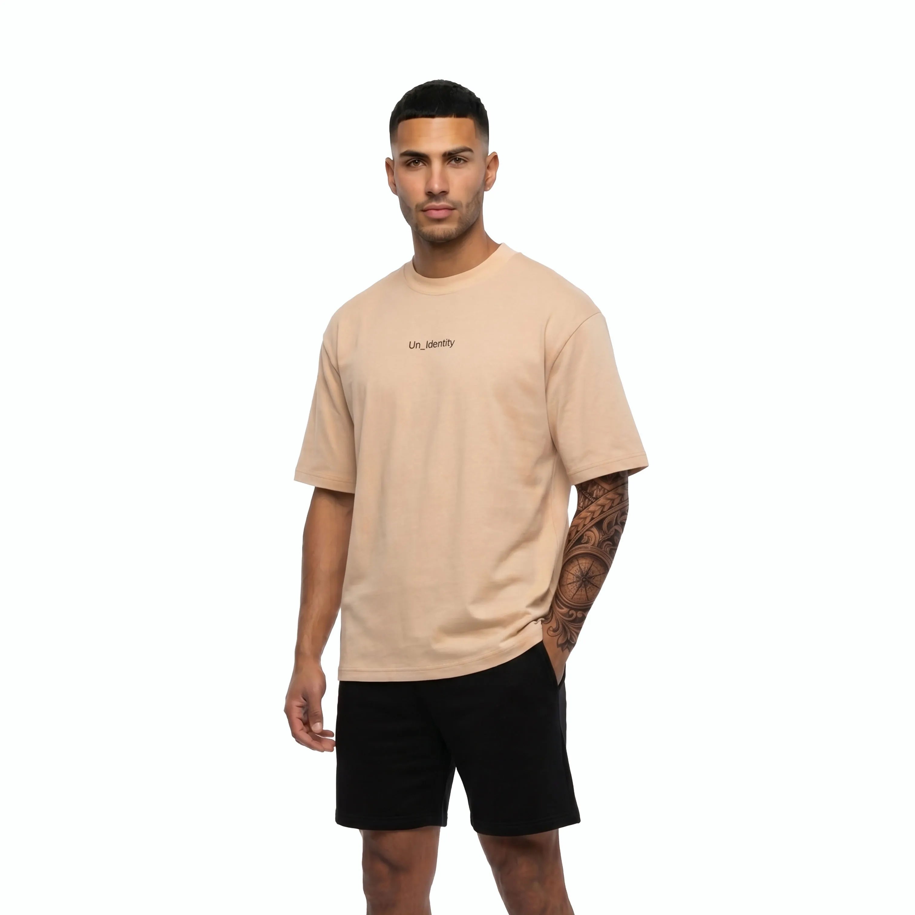 Model wearing beige tee with Unidentity logo on the chest and black shorts. #color_beige