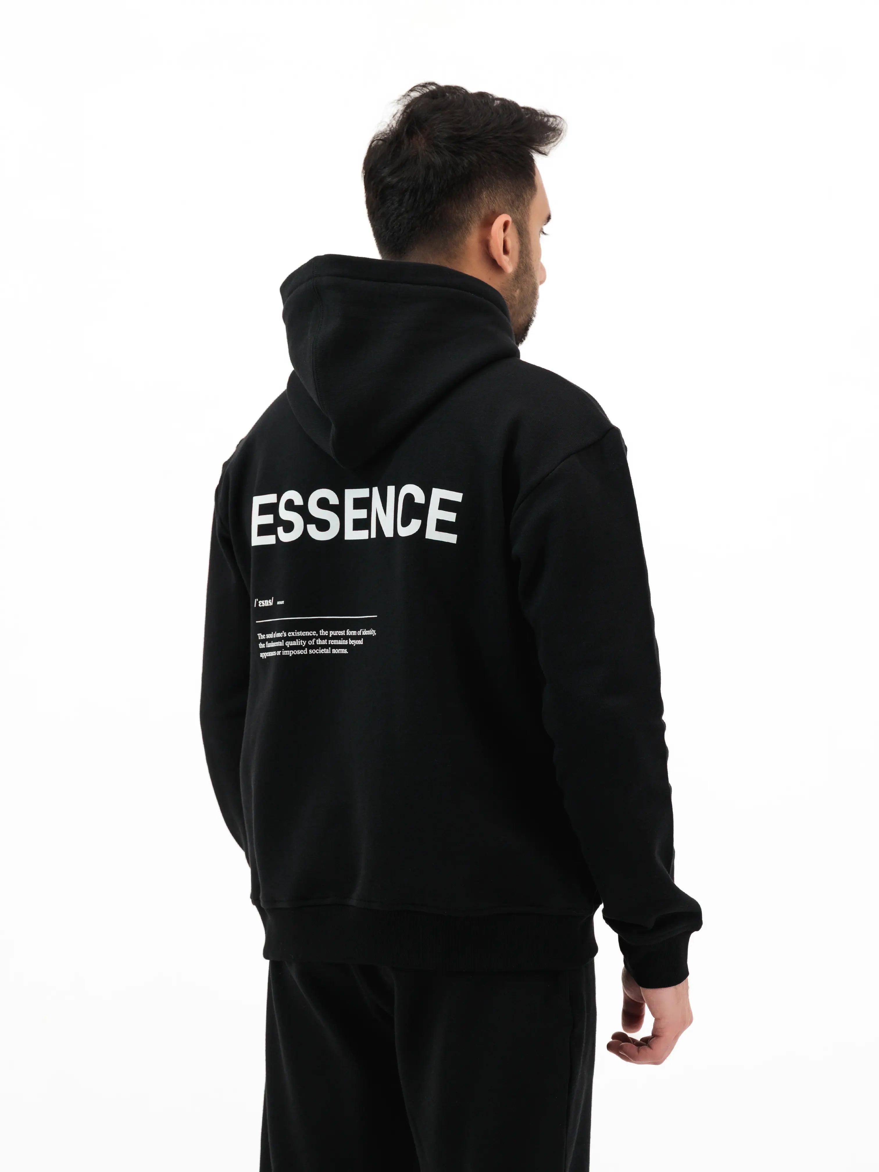 Man wearing black hoodie with ESSENCE text on the back. #color_black