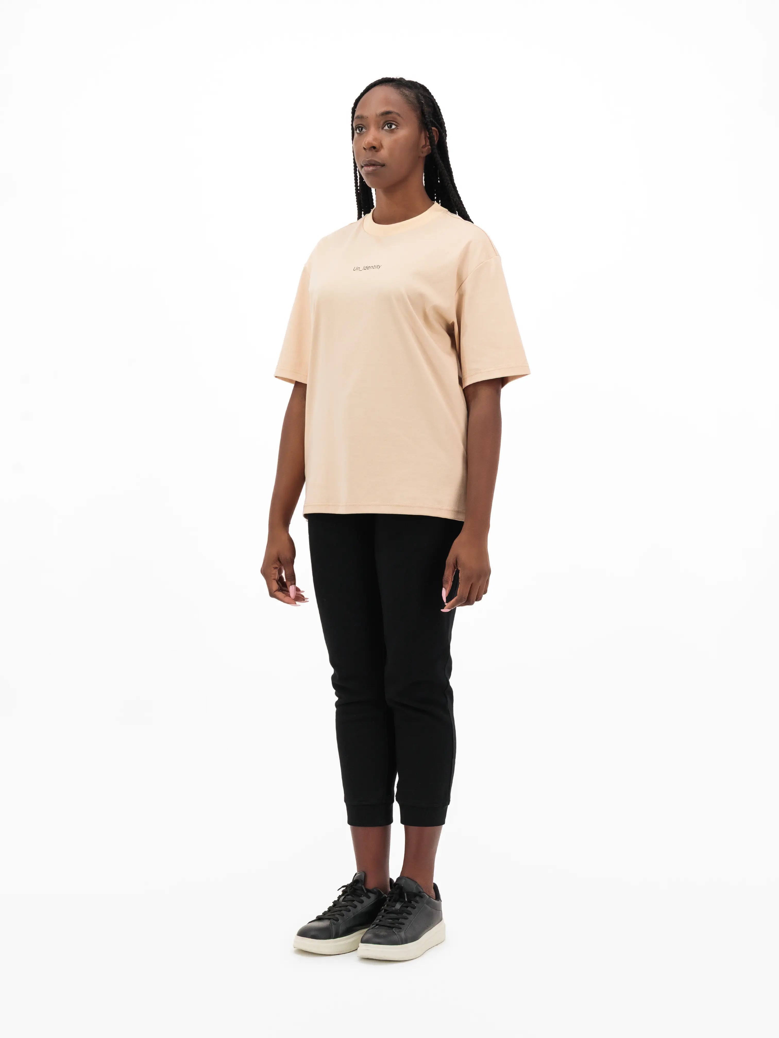 Model wearing beige tee with Unidentity logo on the chest and black pants