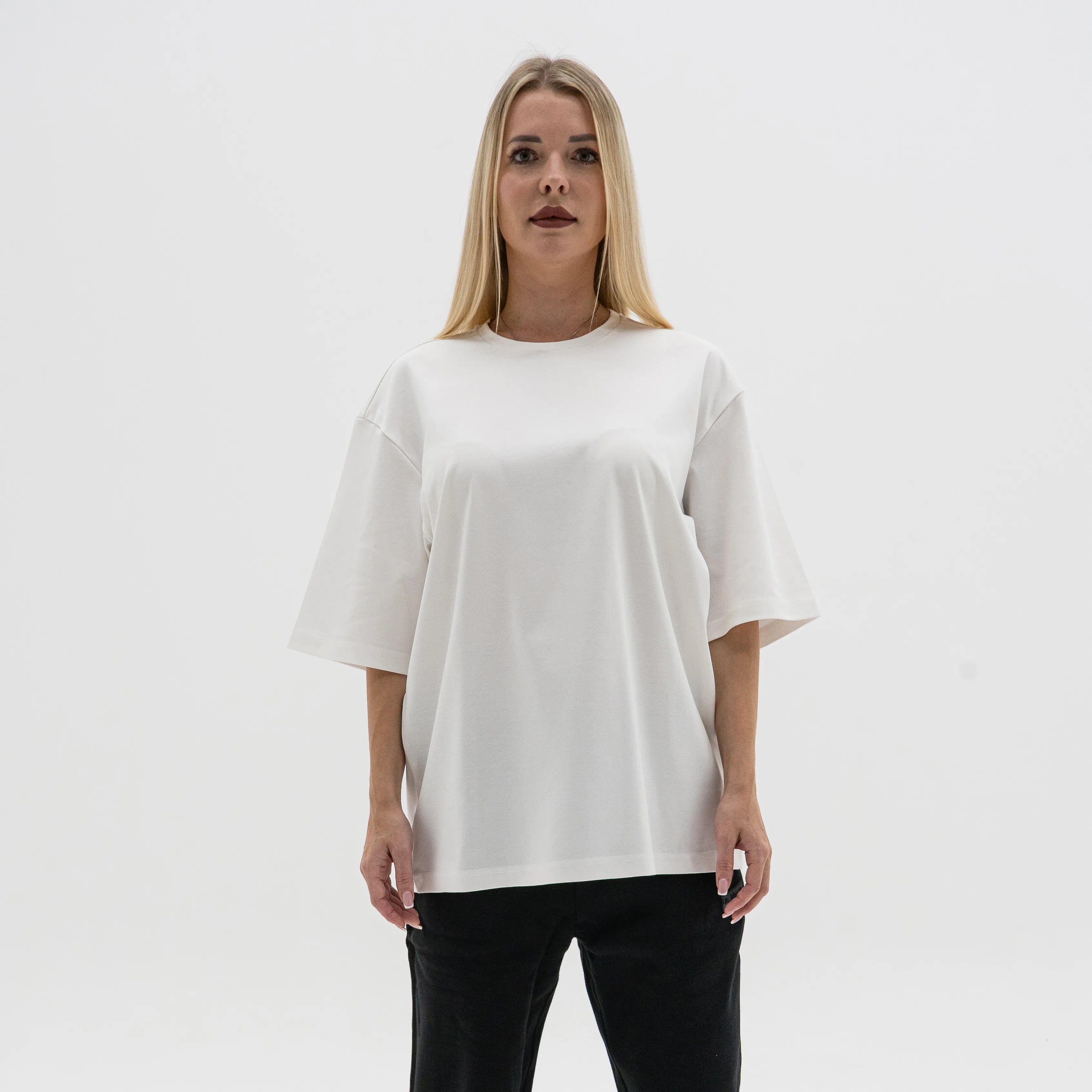 Woman wearing a white oversized t-shirt against a plain background. #color_white