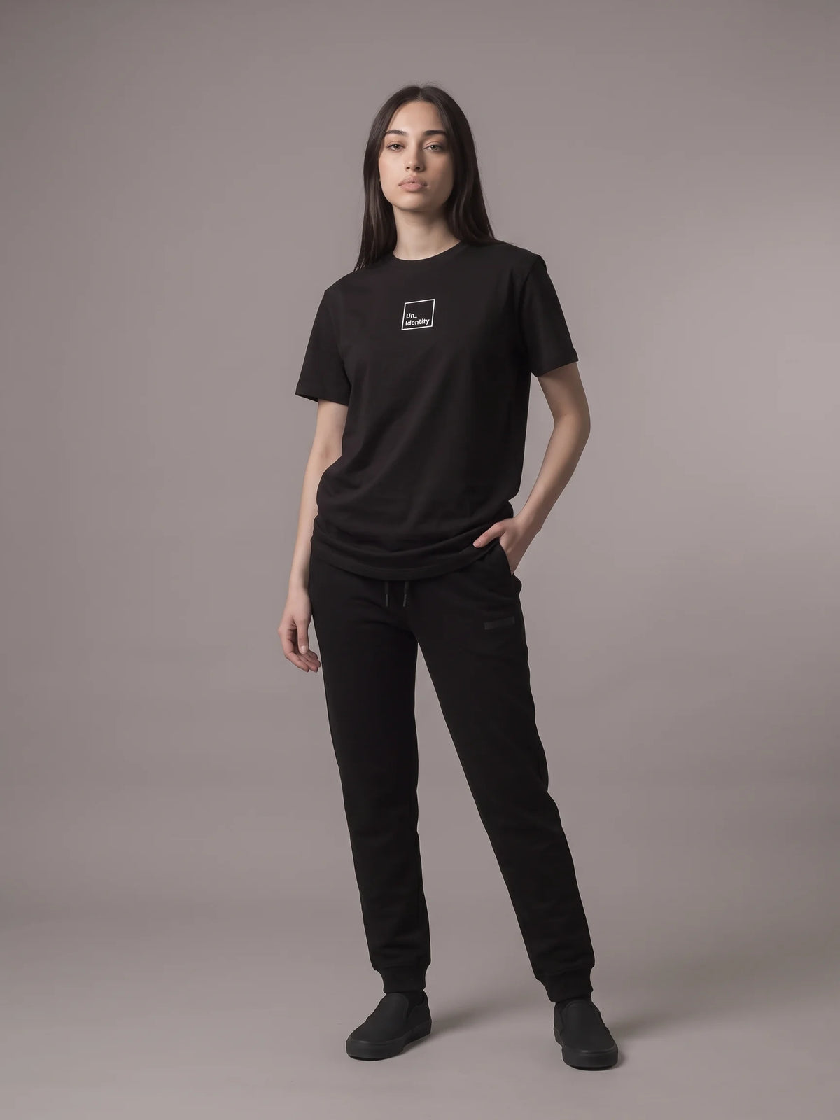Black long fit t-shirt, Unidentity Core Long Fit Tee, full-length front view worn by woman with black Core Regular Fit Joggers, sustainable streetwear #color_black