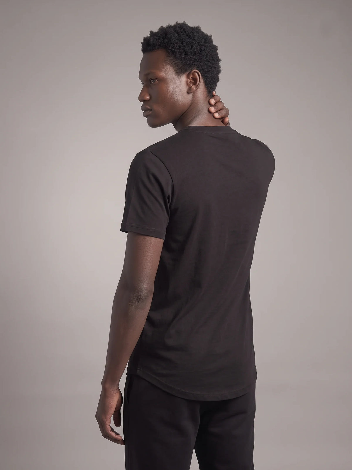Black organic cotton t-shirt, Unidentity Core Tee, back view over the shoulder on man showing the plain back, UAE streetwear #color_black