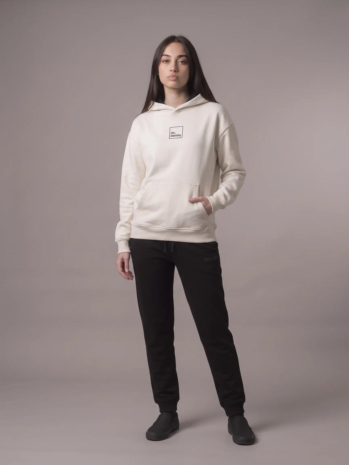 White regular fit hoodie in organic cotton, Unidentity Core Hoodie, full-length front view on woman with black Core joggers, sustainable streetwear #color_white