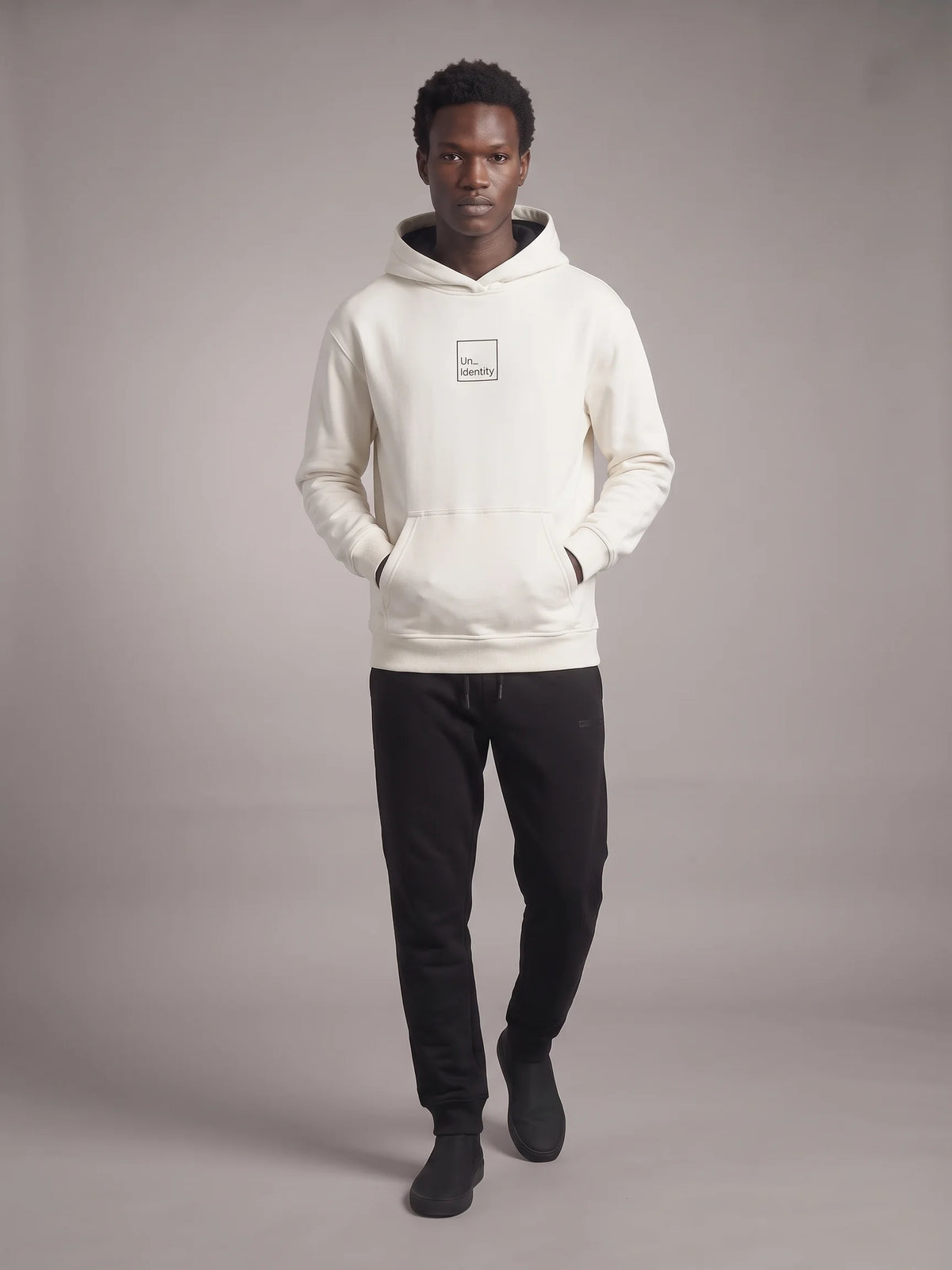 White heavyweight hoodie, Unidentity Core Regular Fit Hoodie, full-length front view on man with black Core Regular Fit Joggers, streetwear from Dubai #color_white