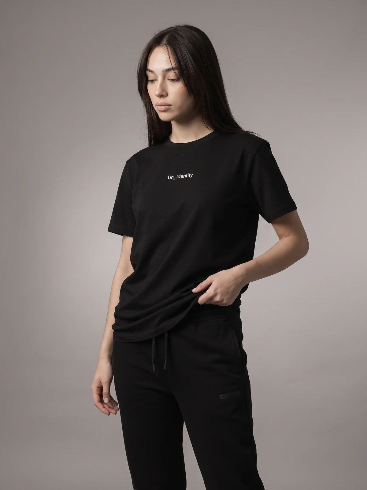 Black organic cotton t-shirt, Unidentity Gem Tee, front view worn by woman with small white Un_Identity chest wordmark, sustainable fashion #color_black