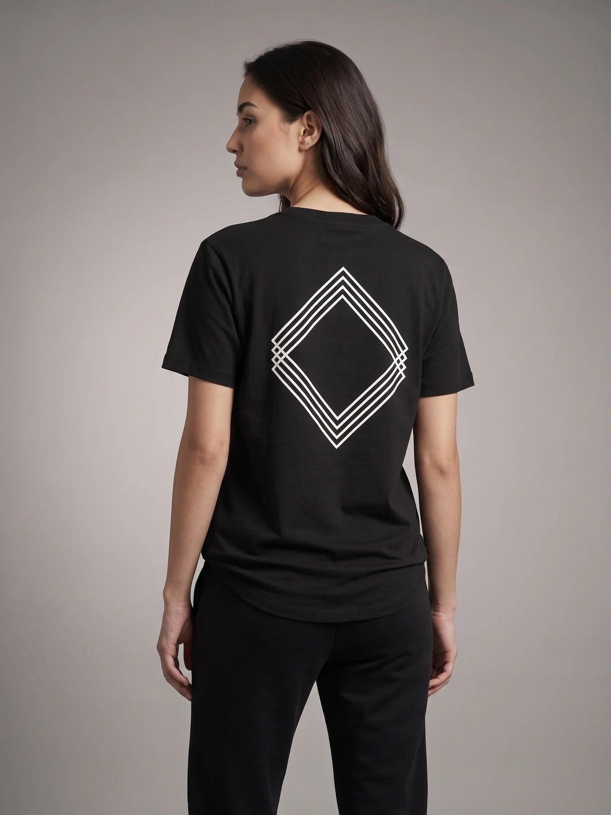 Black long fit t-shirt in organic cotton, Unidentity Gem Tee, back view worn by woman with large white diamond logo print, 210gsm UAE streetwear #color_black