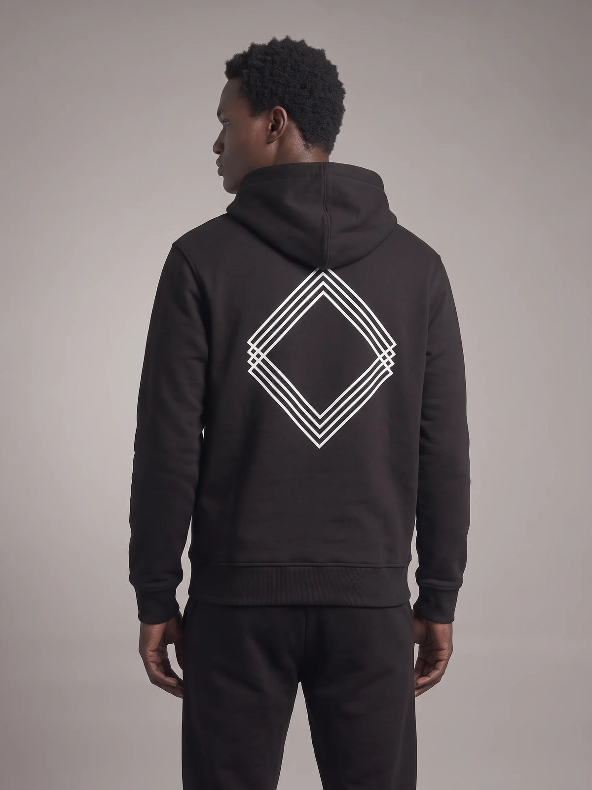 Black regular fit hoodie, Unidentity Gem Regular Fit Hoodie, back view on man showing the white triple-line diamond logo below the hood, streetwear #color_black