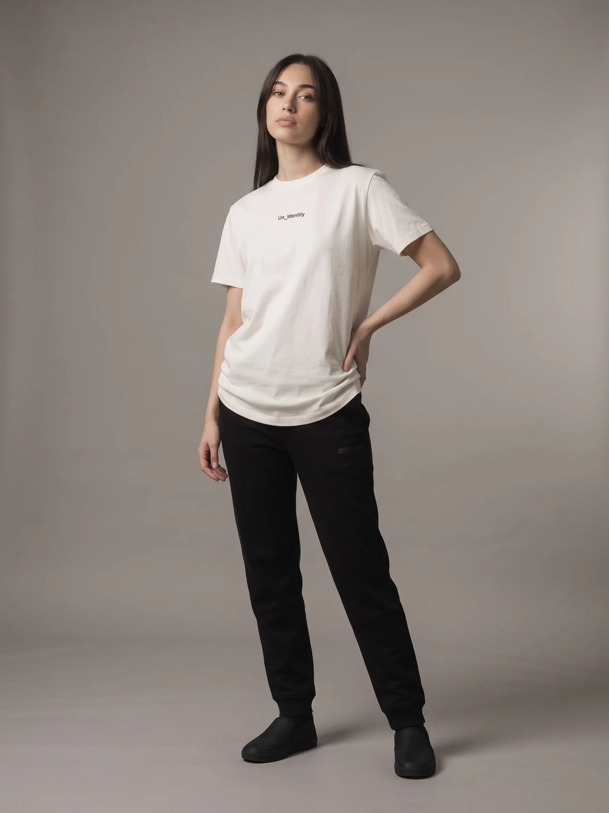 White organic cotton t-shirt, Unidentity Gem Tee, full-length front view worn by woman, hand on hip, with black Core joggers, UAE streetwear #color_white