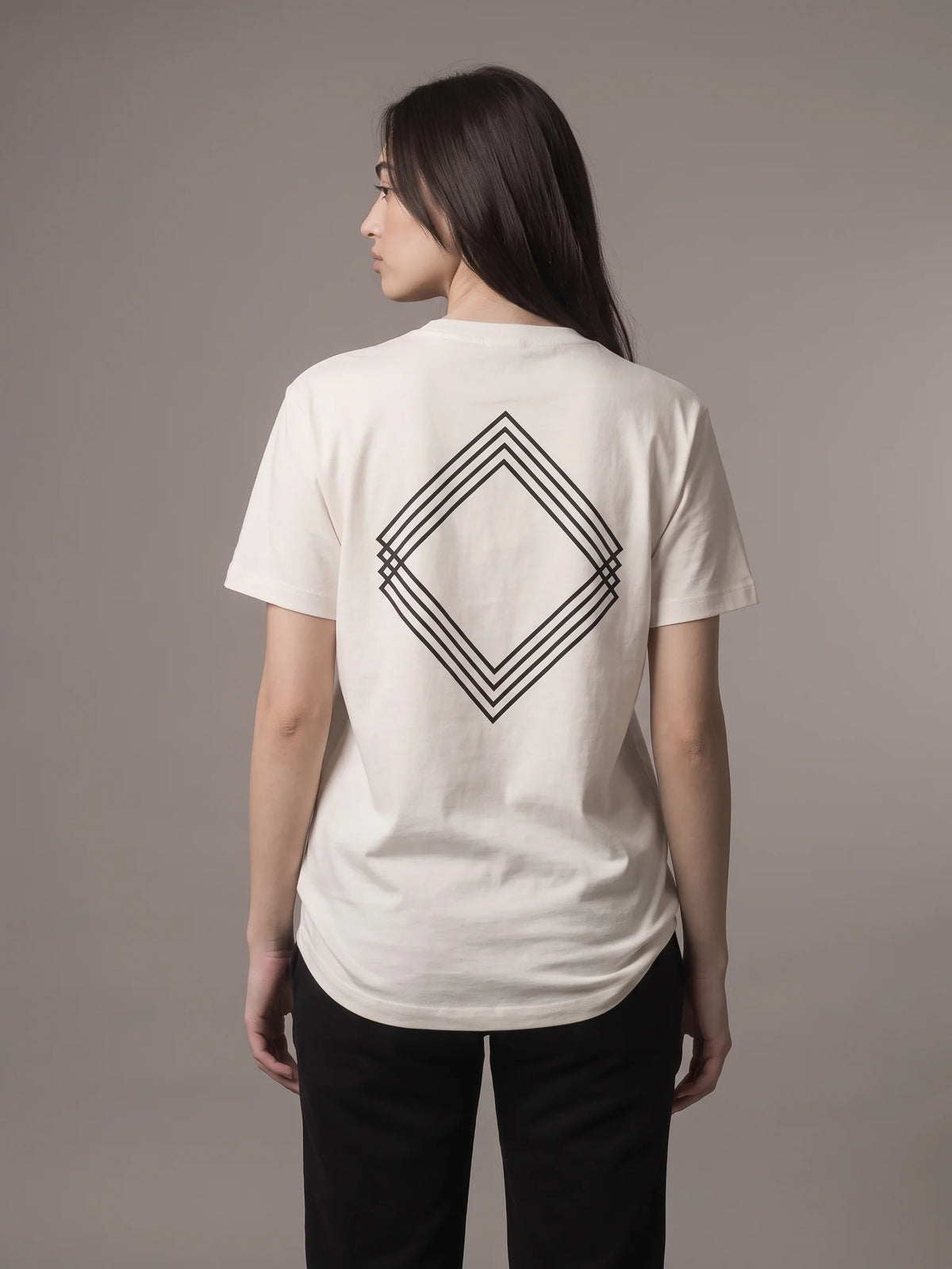 White long fit t-shirt, Unidentity Gem Long Fit Tee, back view worn by woman showing the large black triple-line diamond logo, organic cotton #color_white