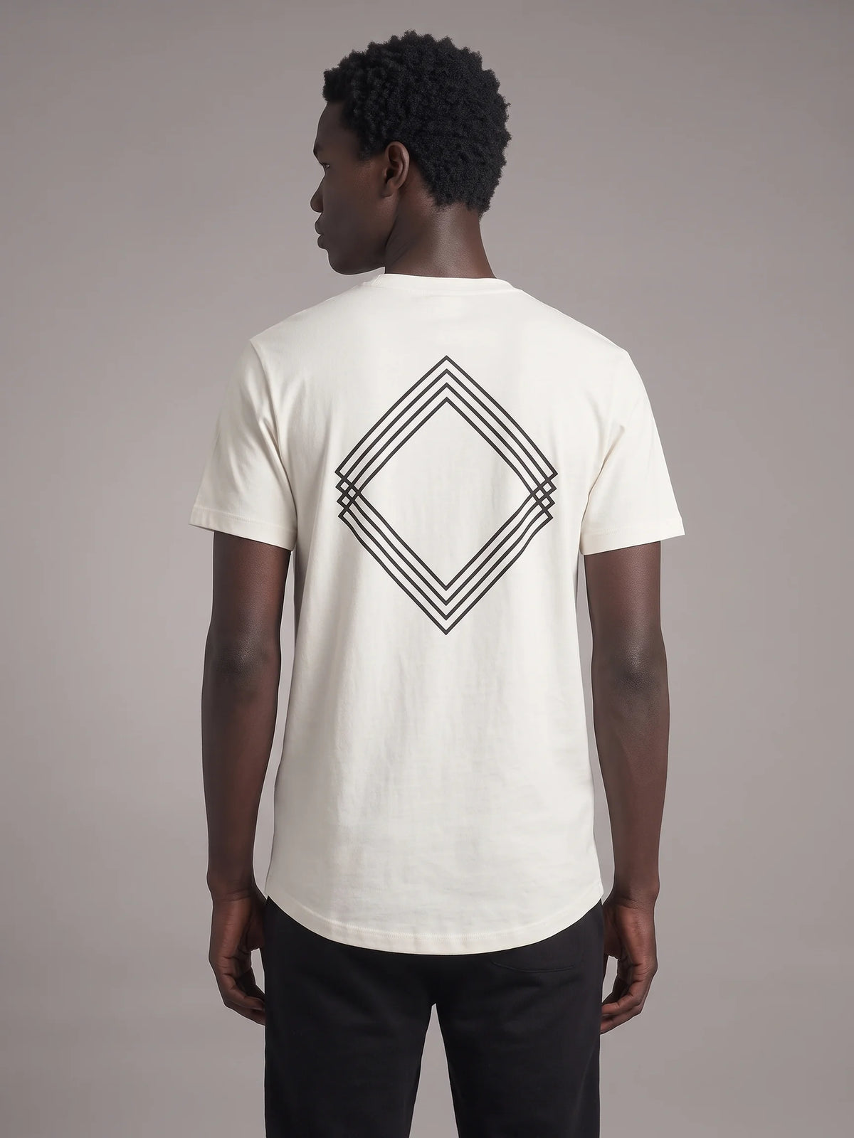 White long fit t-shirt in organic cotton, Unidentity Gem Tee, back view on man with black layered diamond logo print, 210gsm streetwear from the UAE #color_white