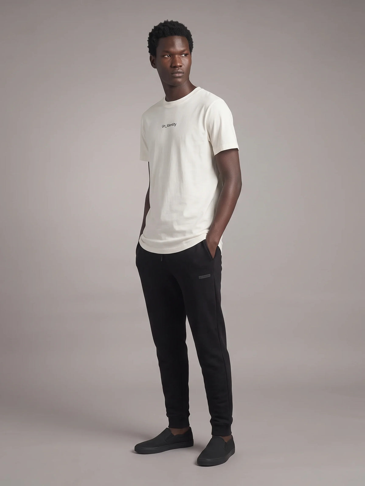 White long fit t-shirt, Unidentity Gem Long Fit Tee, full-length front view on man styled with black Core Regular Fit Joggers, sustainable streetwear #color_white
