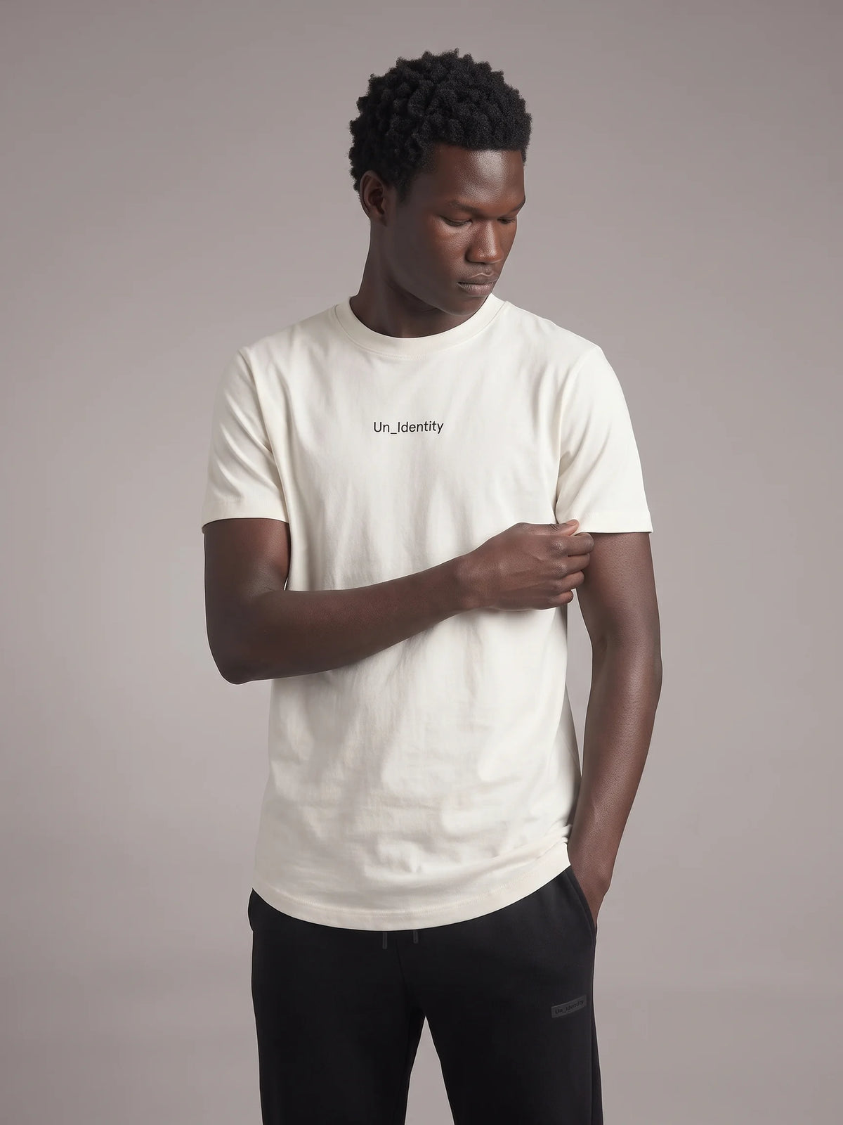 White organic cotton t-shirt, Unidentity Gem Tee, front view on man with black Un_Identity chest wordmark, streetwear brand in Dubai #color_white