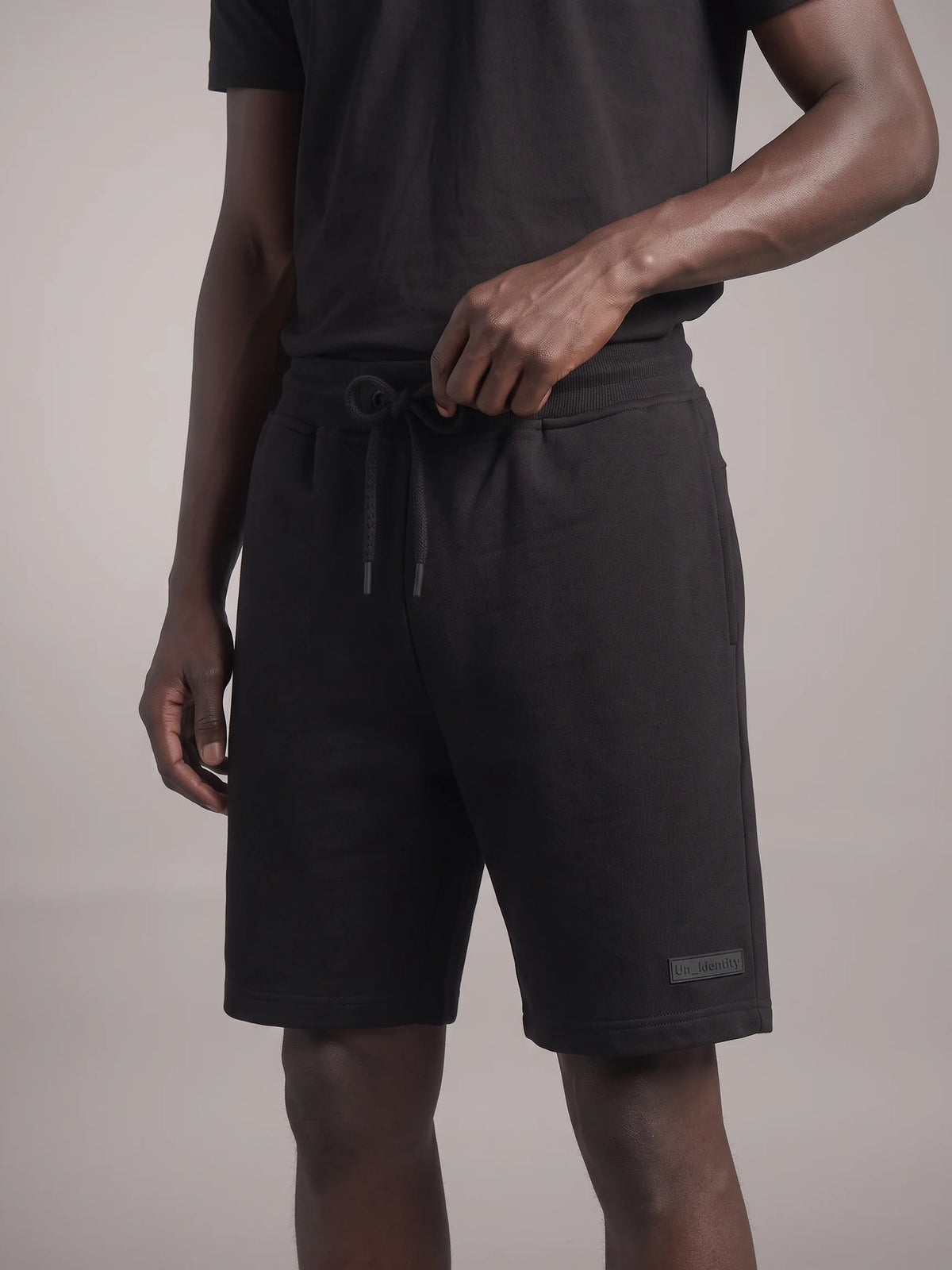 Black heavyweight sweat shorts in organic cotton, Unidentity Core Shorts, front close-up of the drawstring on man, 390gsm streetwear from Dubai #color_black