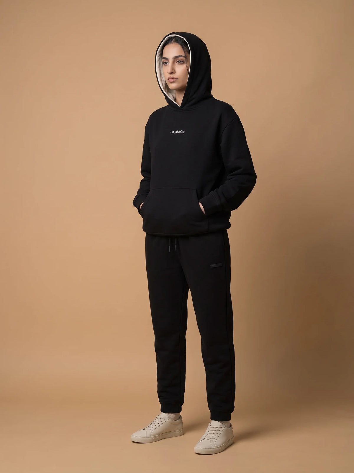 Black heavyweight hoodie in organic cotton, Unidentity Soul Hoodie, full-length front view worn by woman with hood up and hands in the pocket, 390gsm #color_black