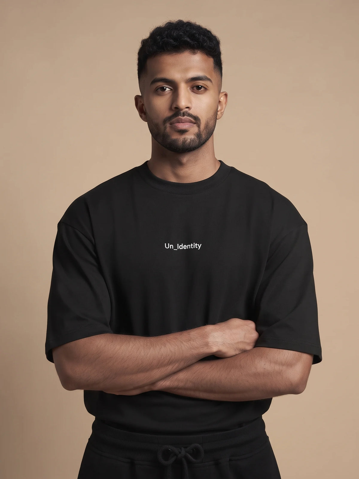 Black oversized t-shirt, Unidentity Soul Oversized Tee, front close-up of the minimal chest logo worn by man with arms crossed, UAE streetwear #color_black