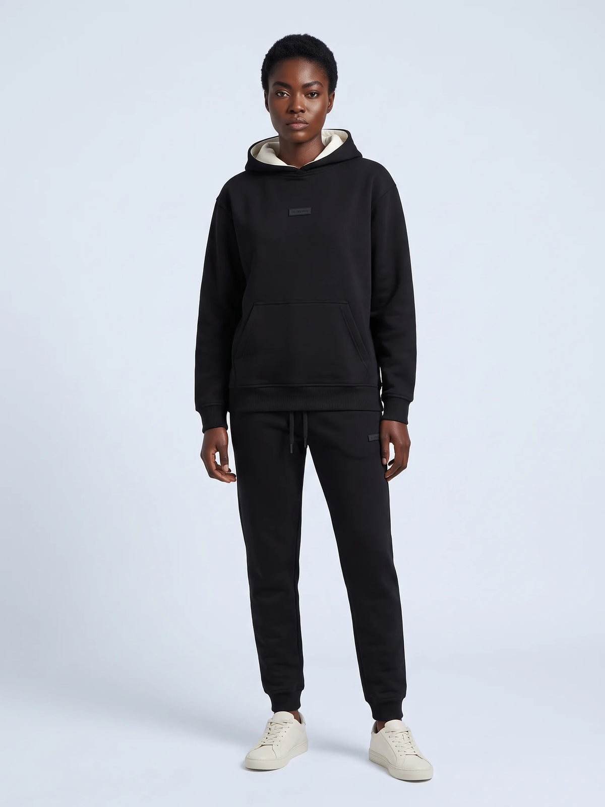 Black heavyweight hoodie, Unidentity Identity Regular Fit Hoodie, full-length front view worn by woman with tonal chest patch, 390gsm #color_black